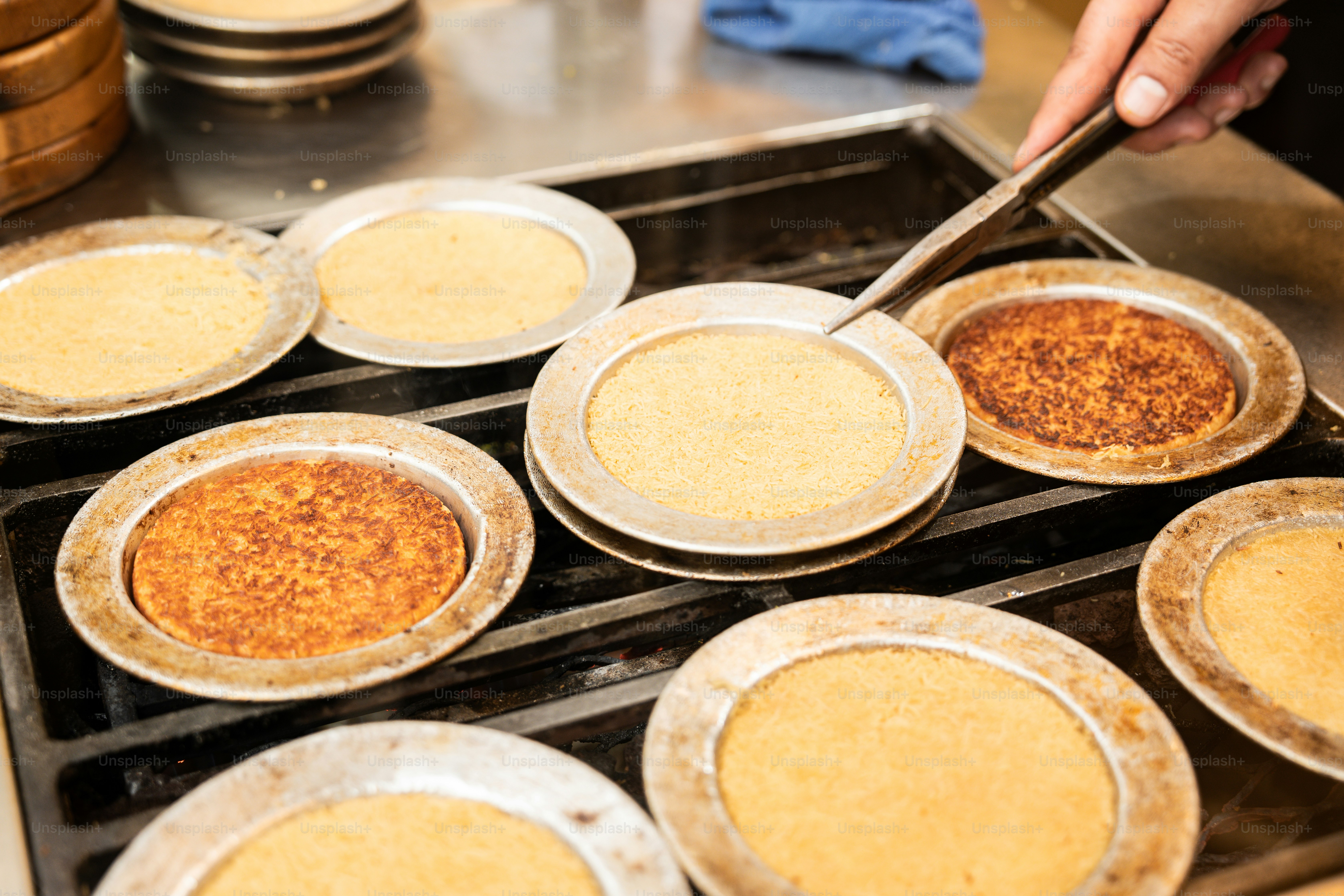 A person putting pies in a pan on a stove
