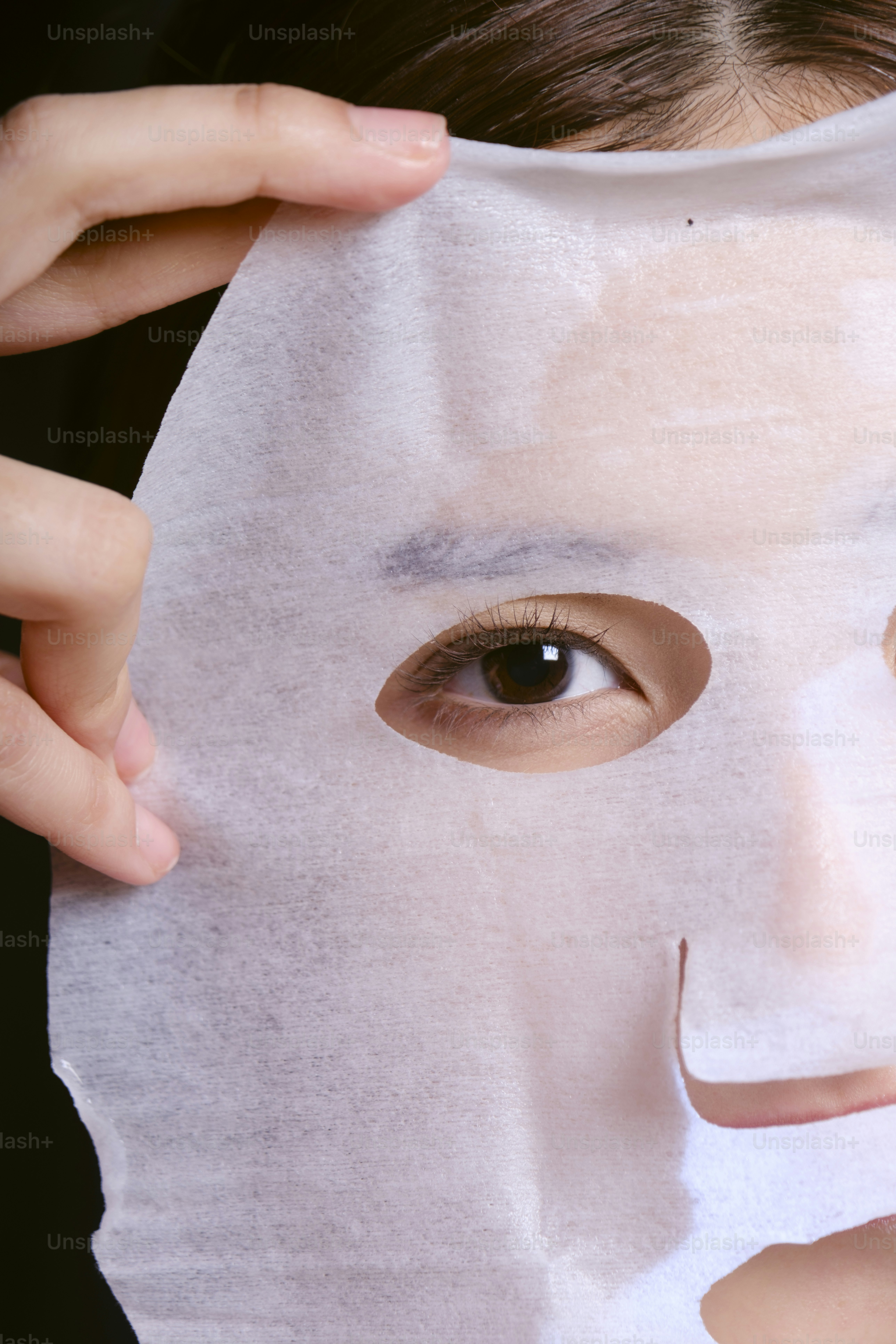 A woman holding a sheet of white paper over her face