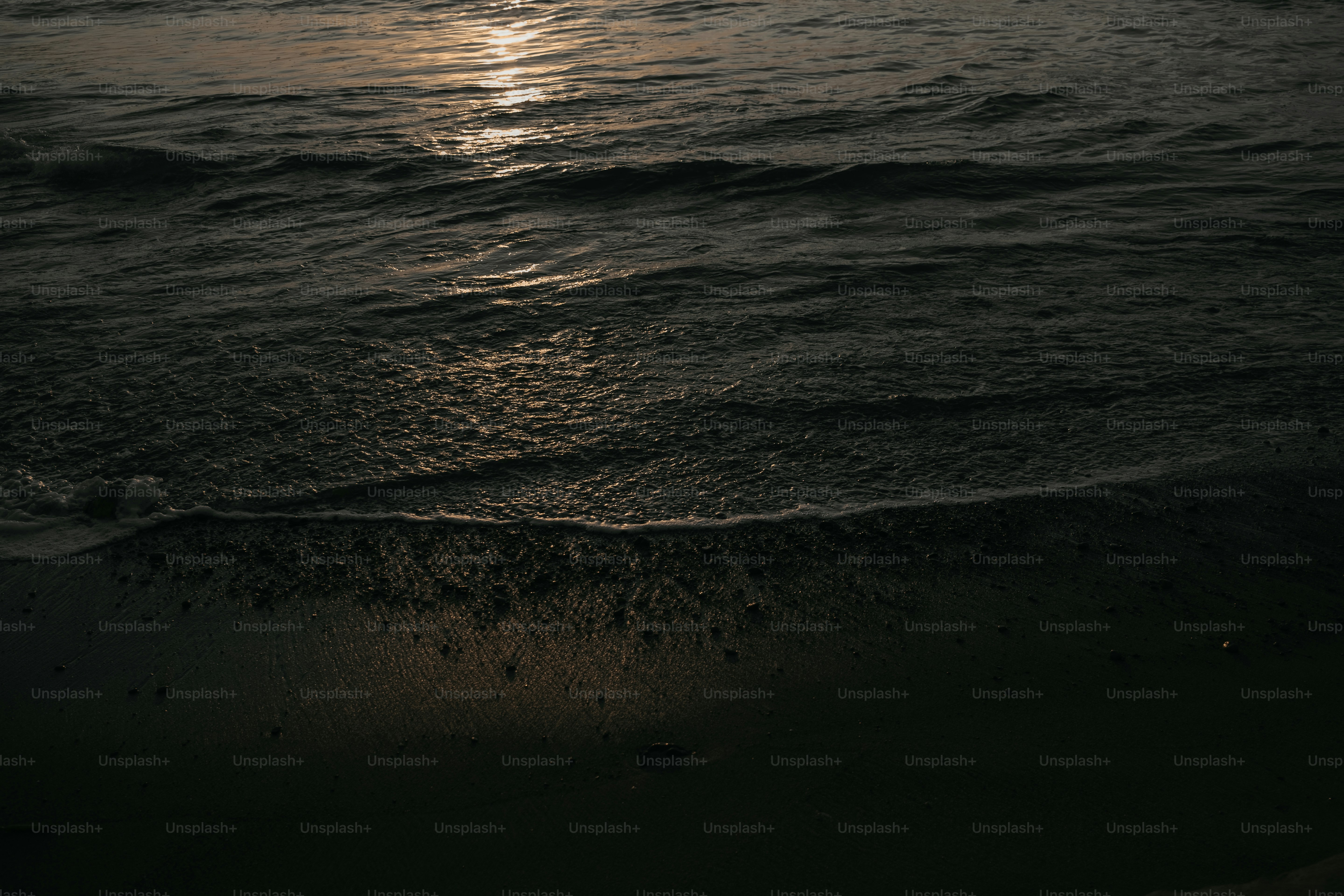 The sun is setting over the water at the beach