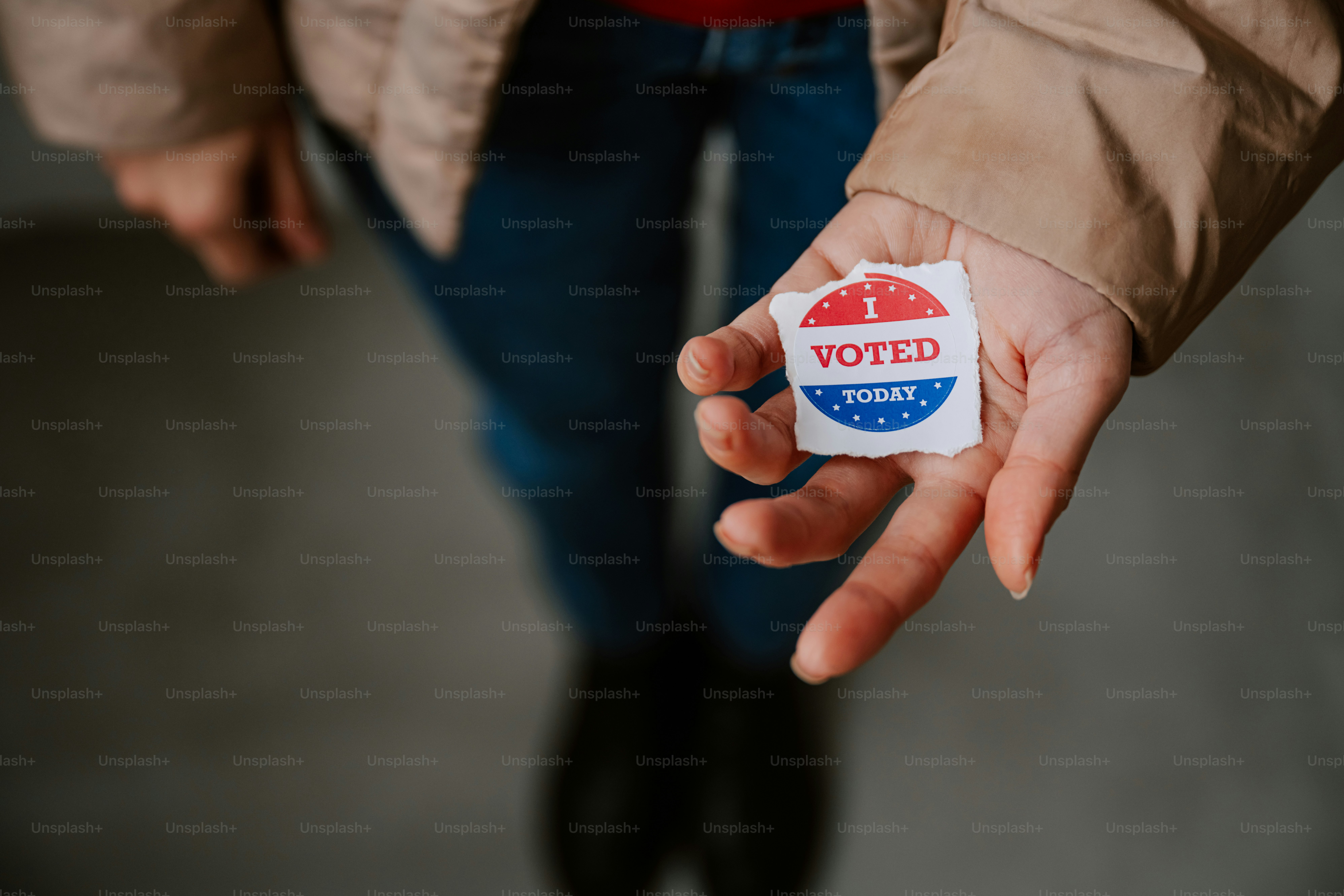 A person holding out their hand with a vote sticker on it