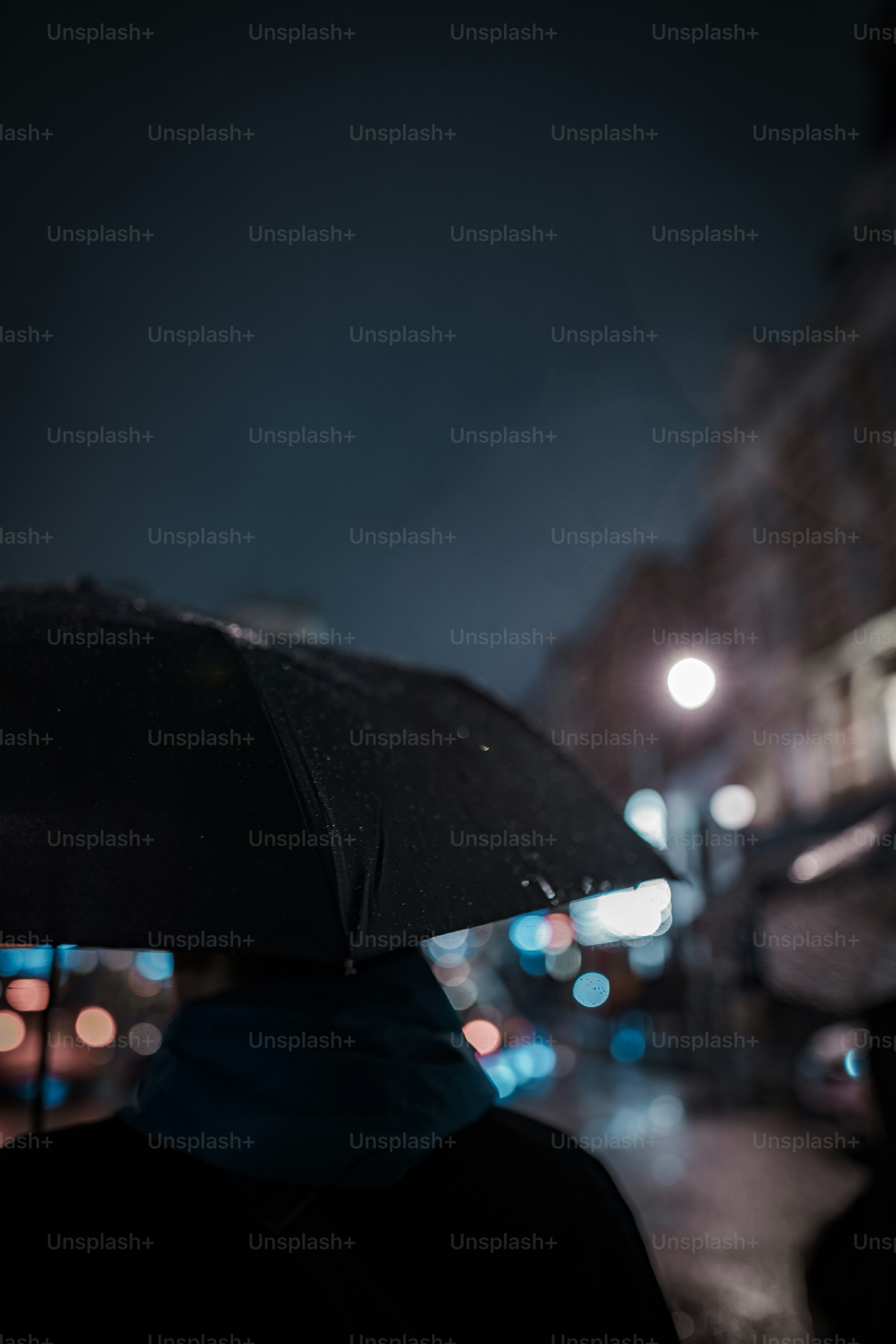 A person holding an umbrella on a city street at night