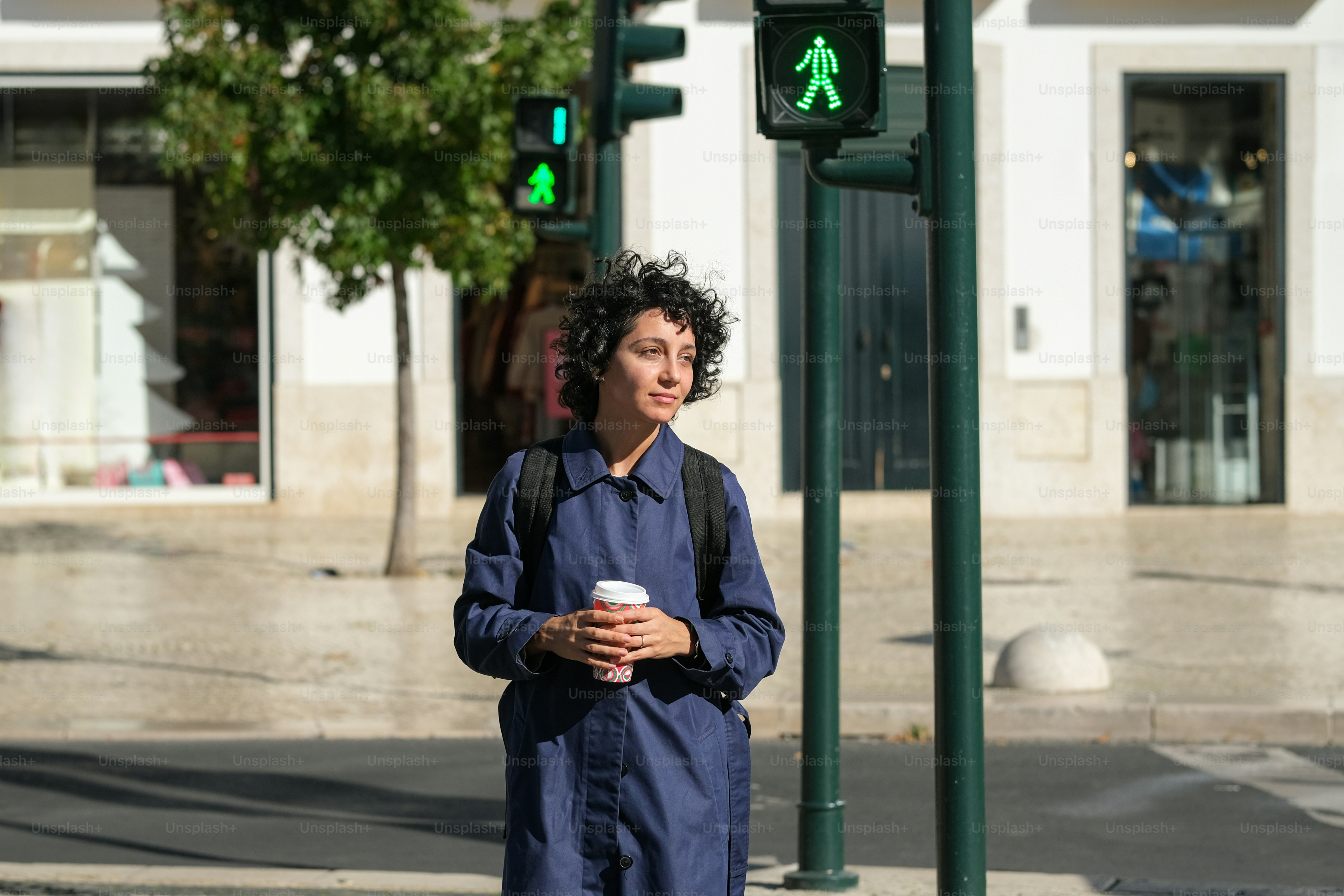 A man standing on the side of a street next to a traffic light