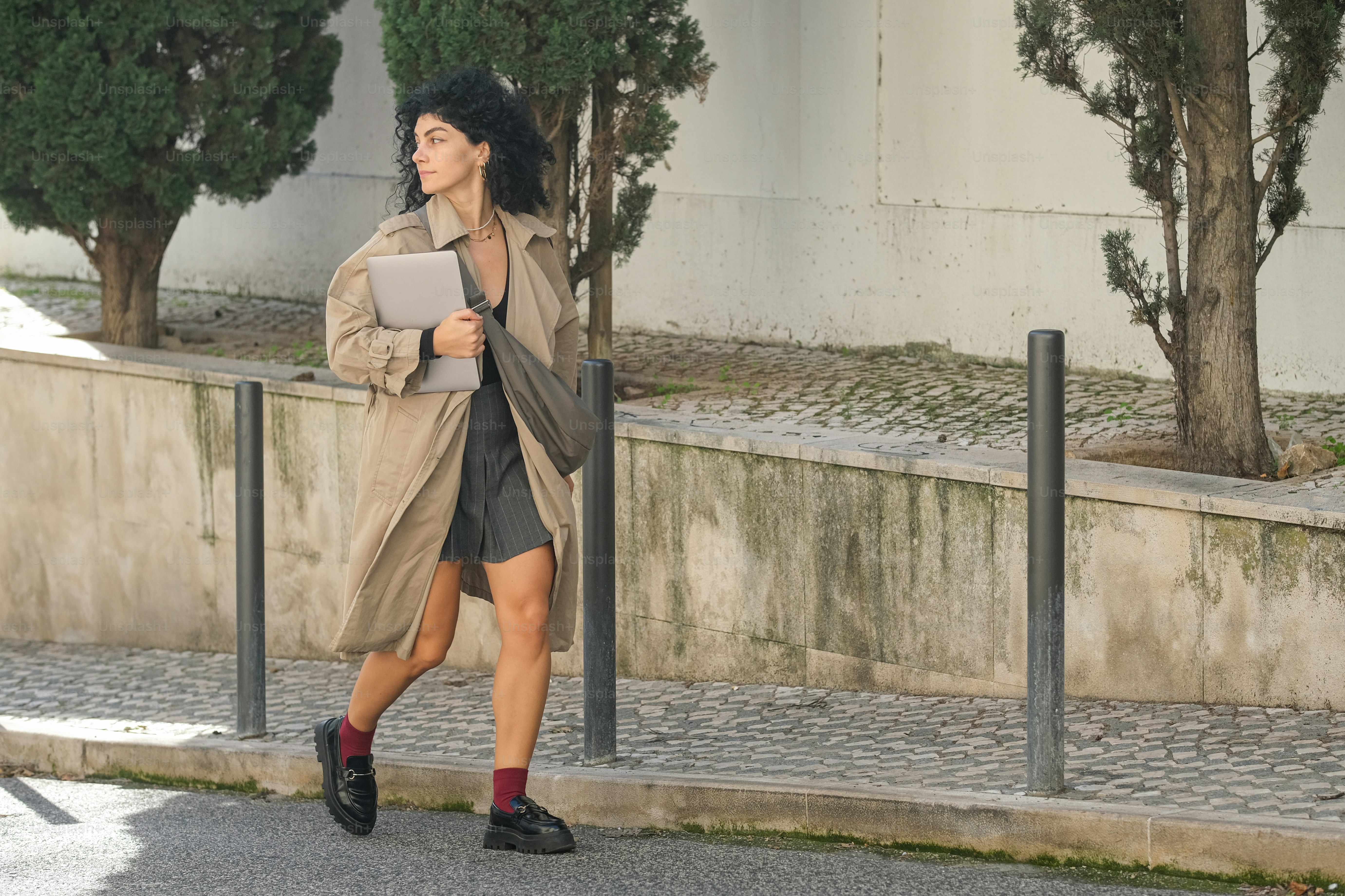 A woman walking down a street while holding a tablet