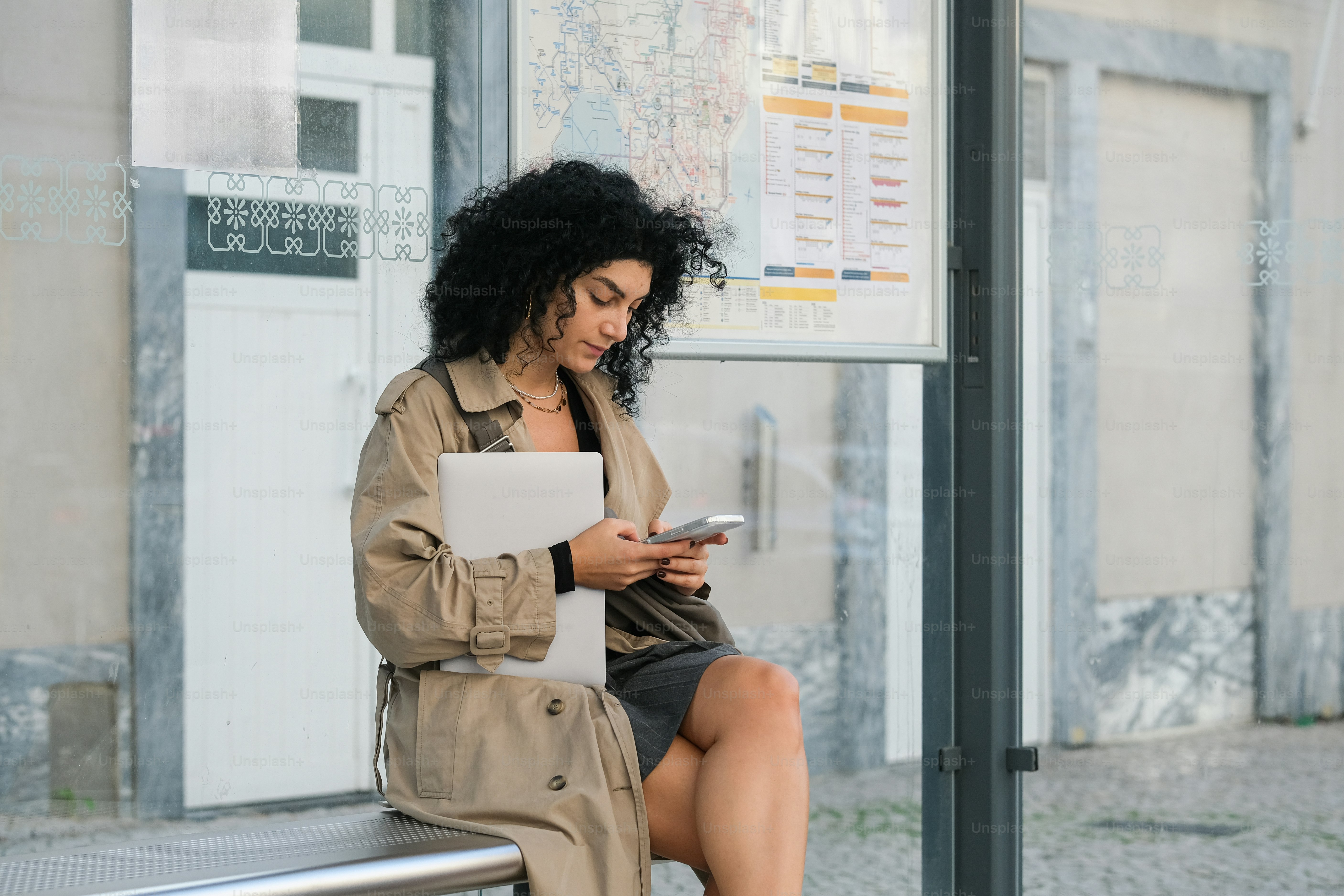A woman sitting on a bench looking at her cell phone