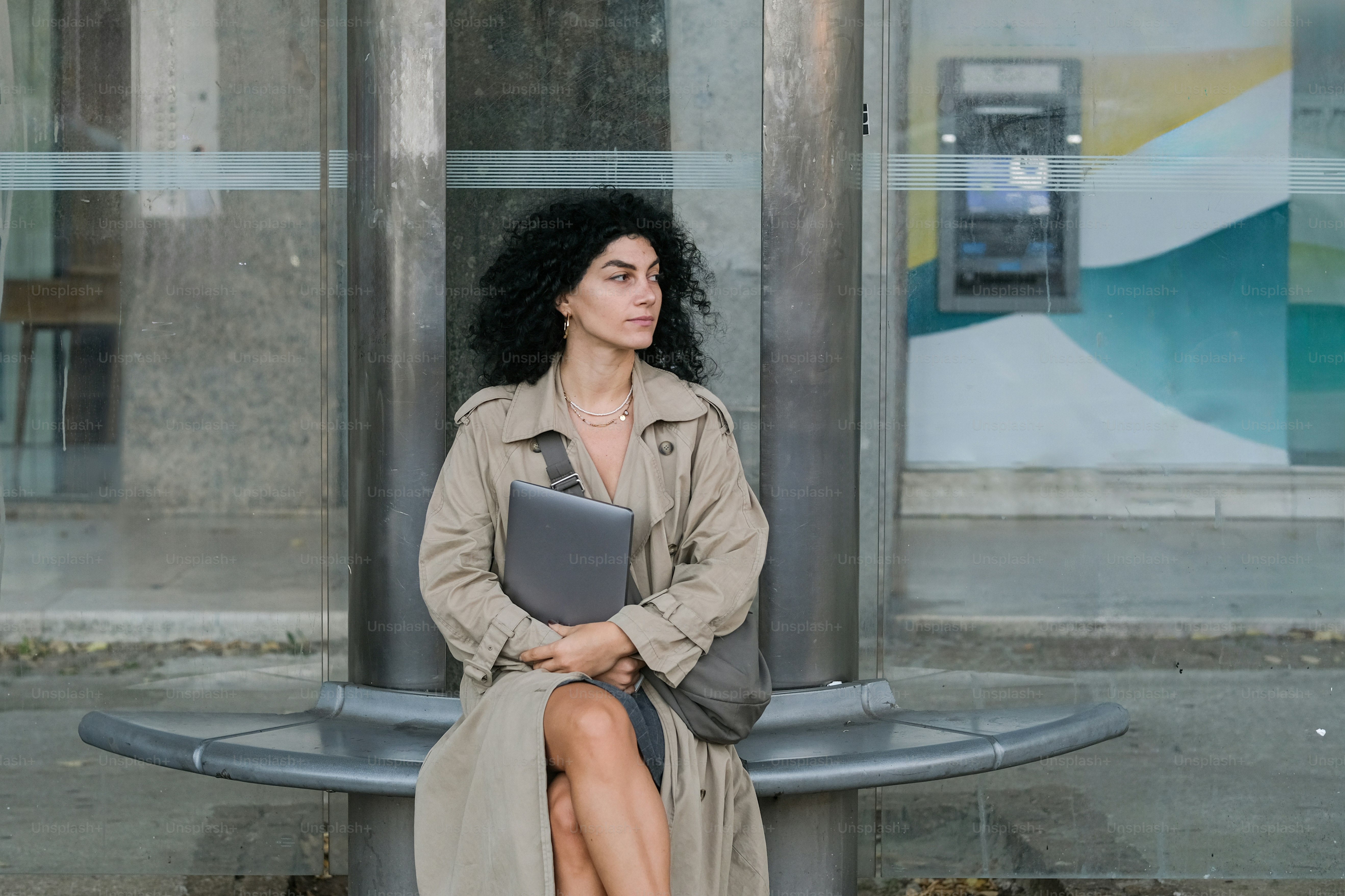 Una donna in un trench seduta su una panchina
