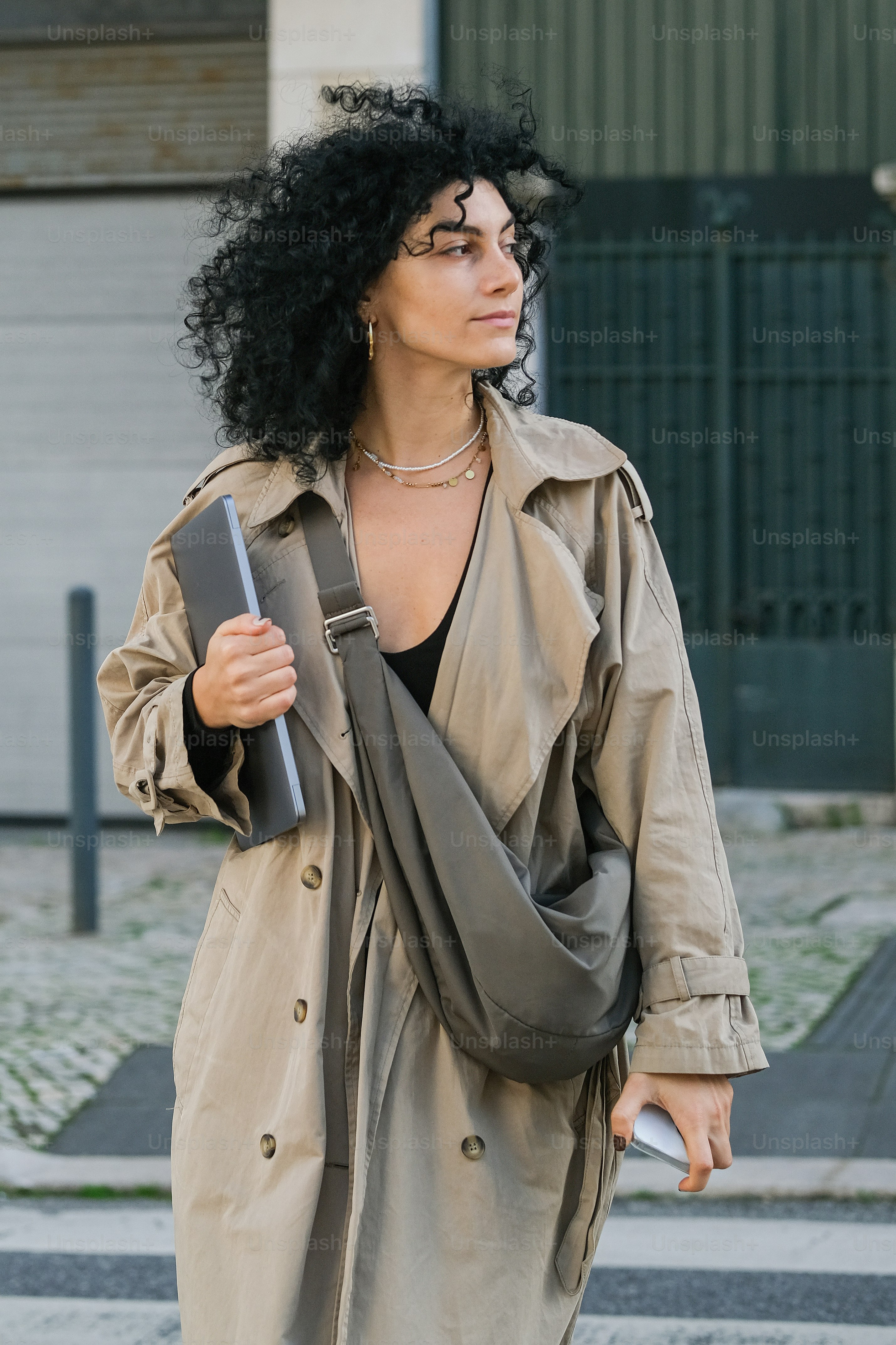 A woman in a trench coat crossing a street