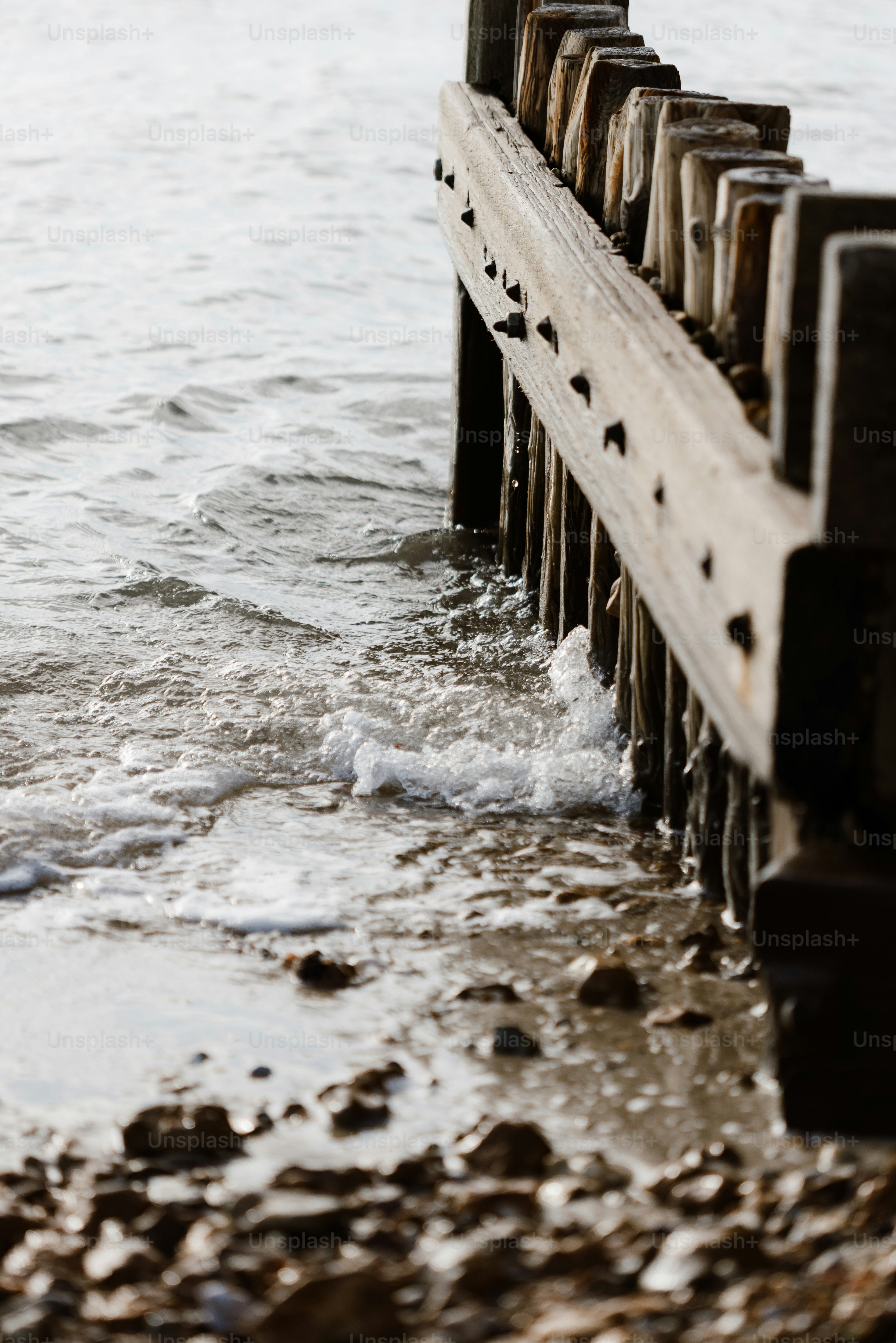 A wooden bench sitting on top of a beach next to the ocean