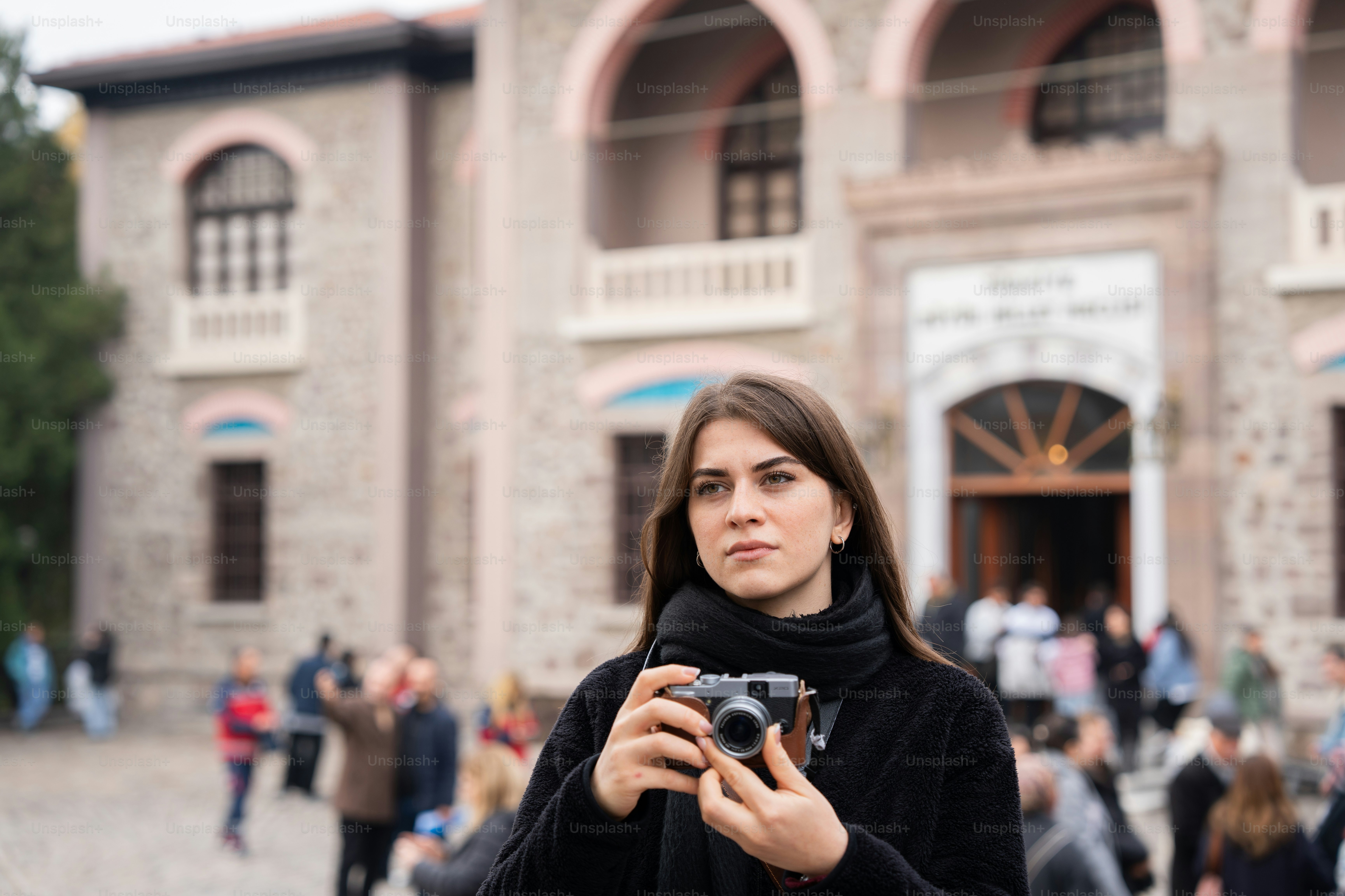 A woman holding a camera in front of a building