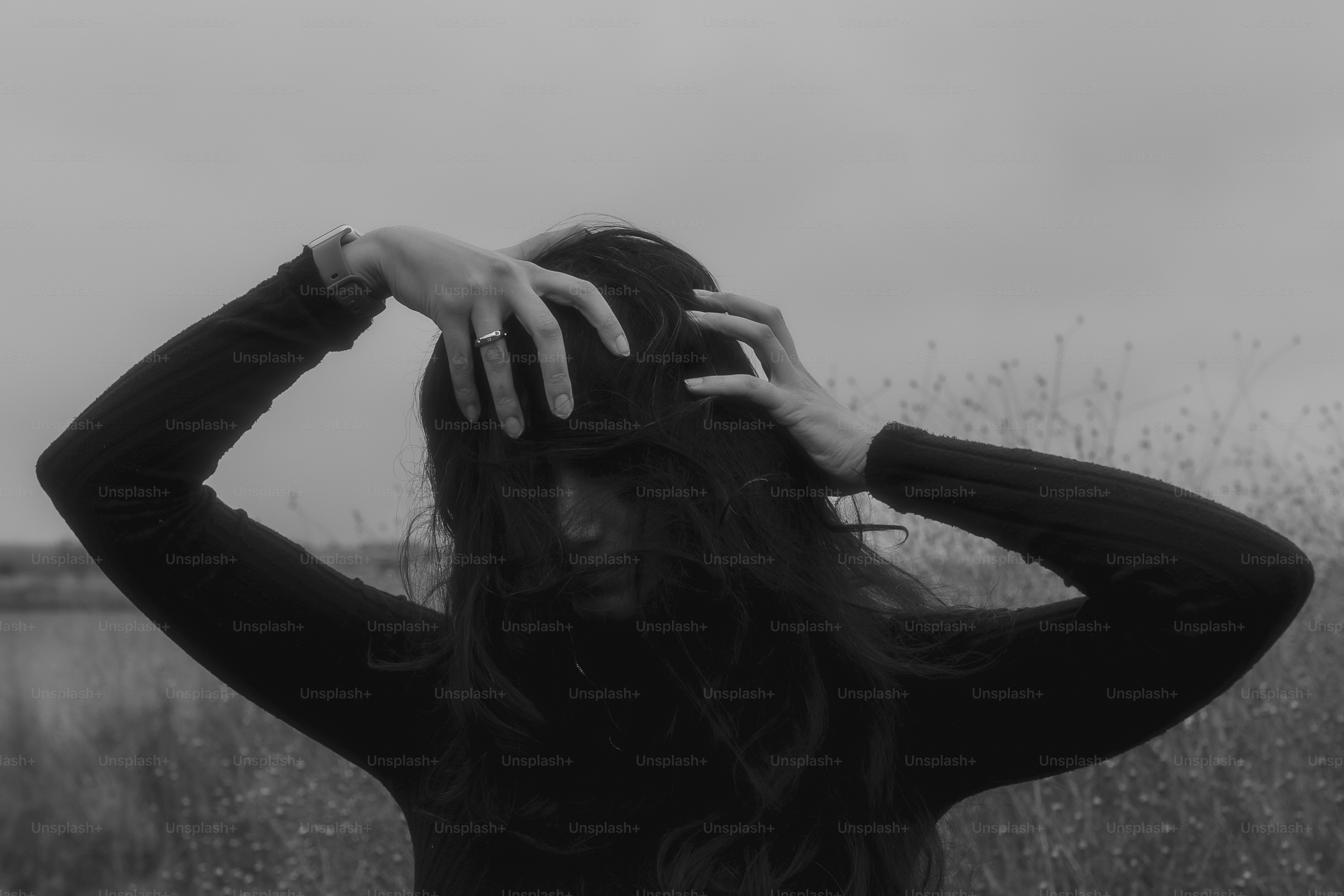 A woman standing in a field with her hands on her head