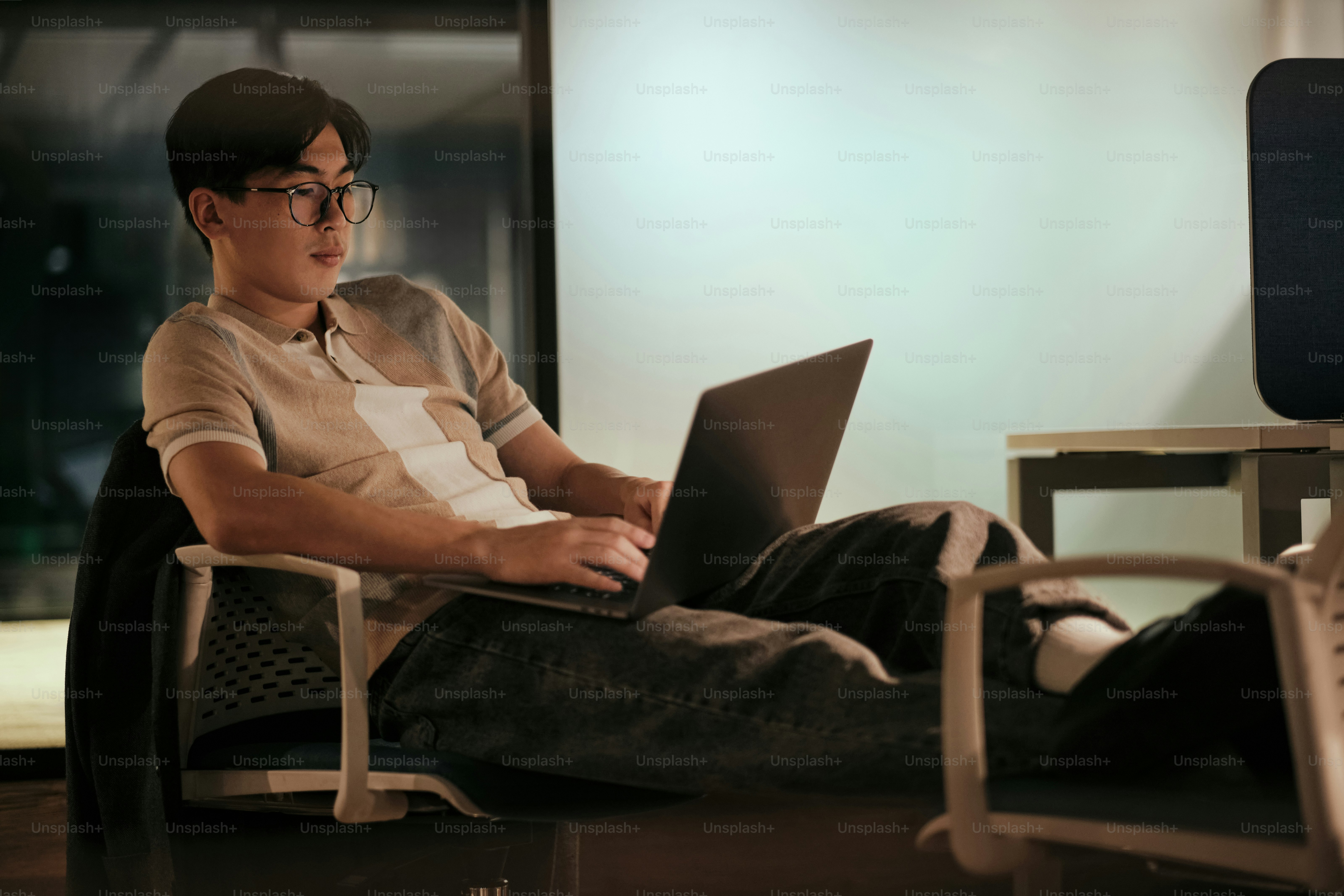 Ein Mann, der auf einem Stuhl sitzt und einen Laptop benutzt