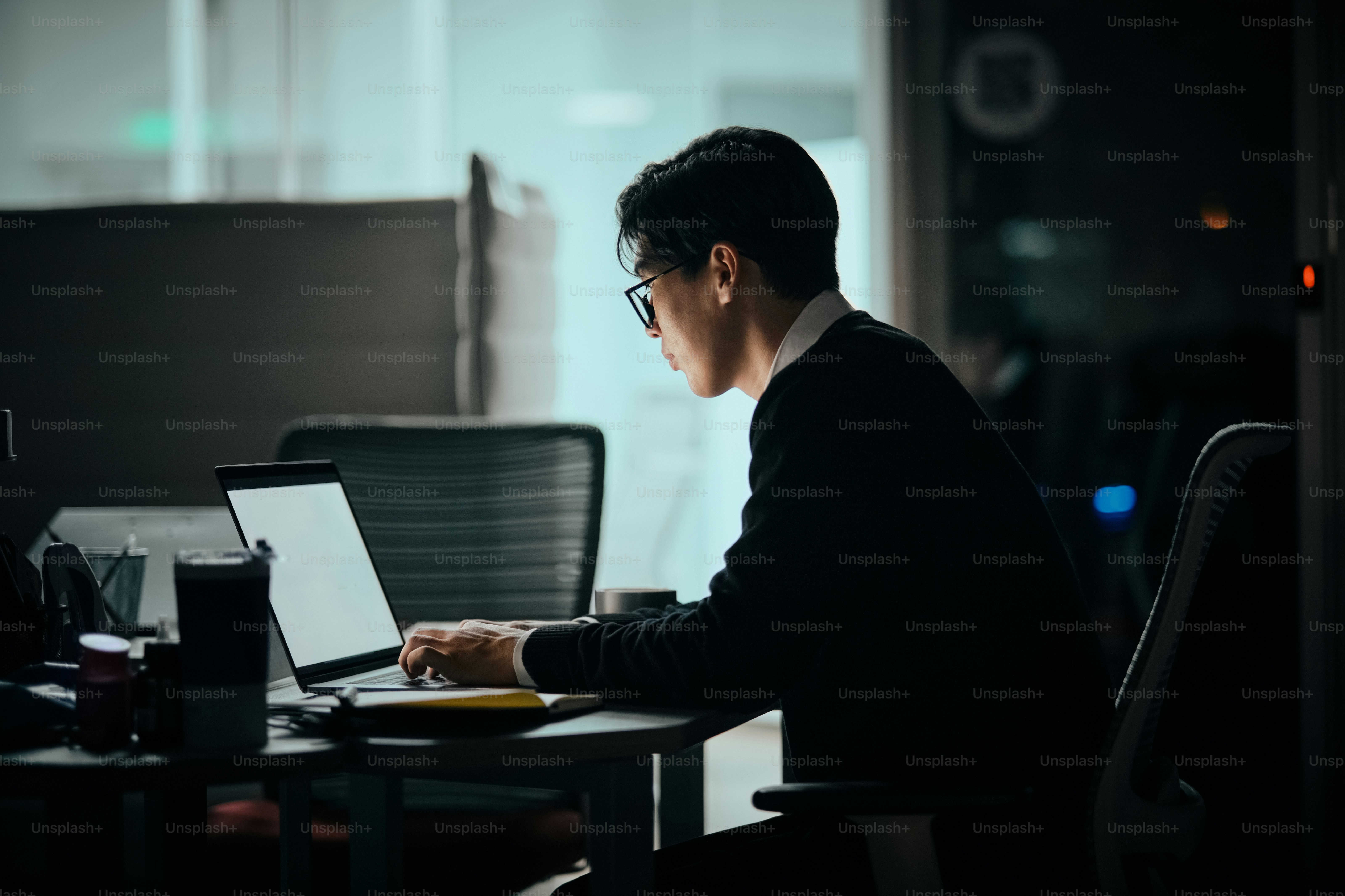 A man sitting at a desk using a laptop computer