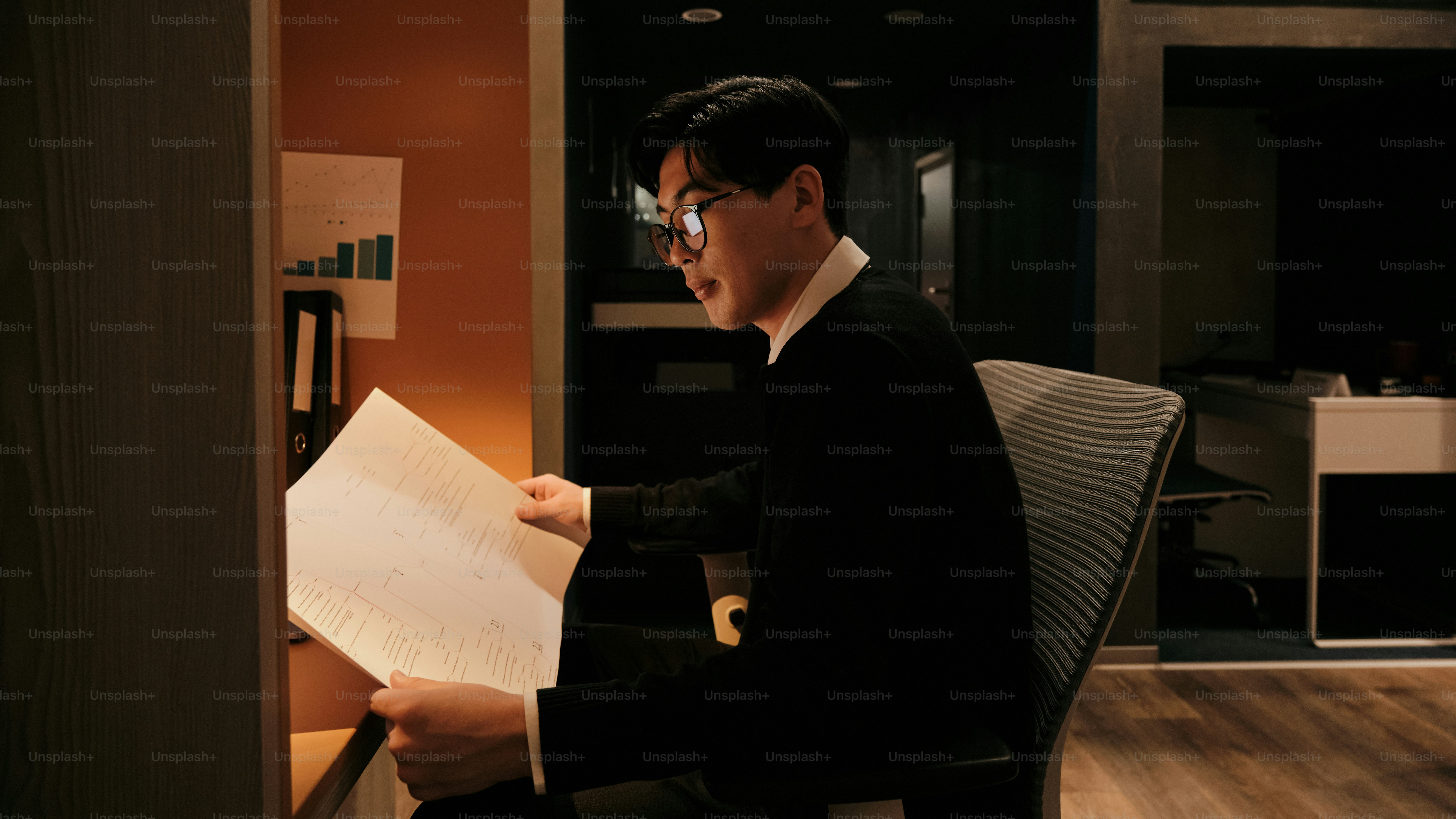 Ein Mann sitzt auf einem Stuhl und hält ein Blatt Papier in der Hand