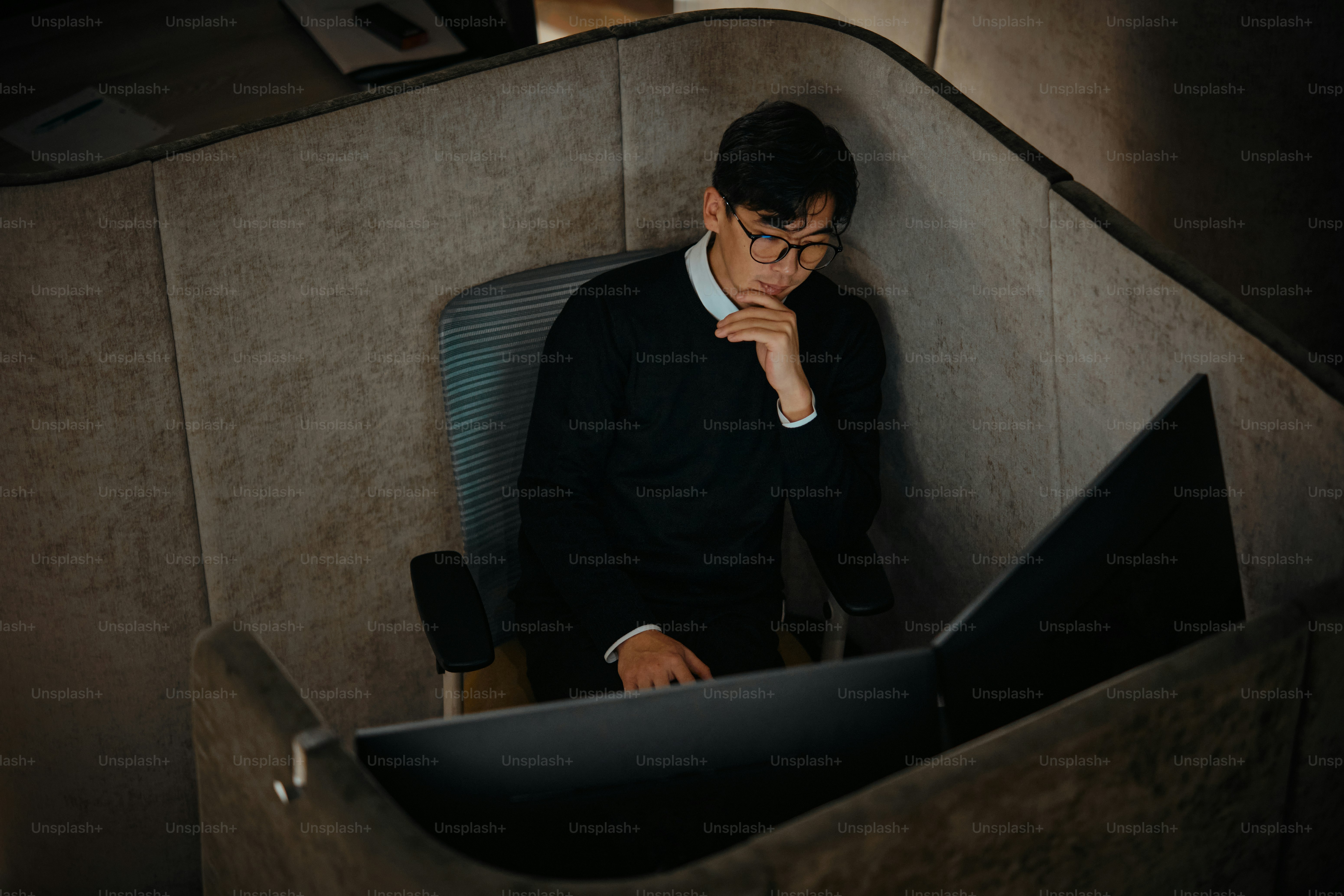 Ein Mann sitzt auf einem Stuhl, die Hand am Kinn