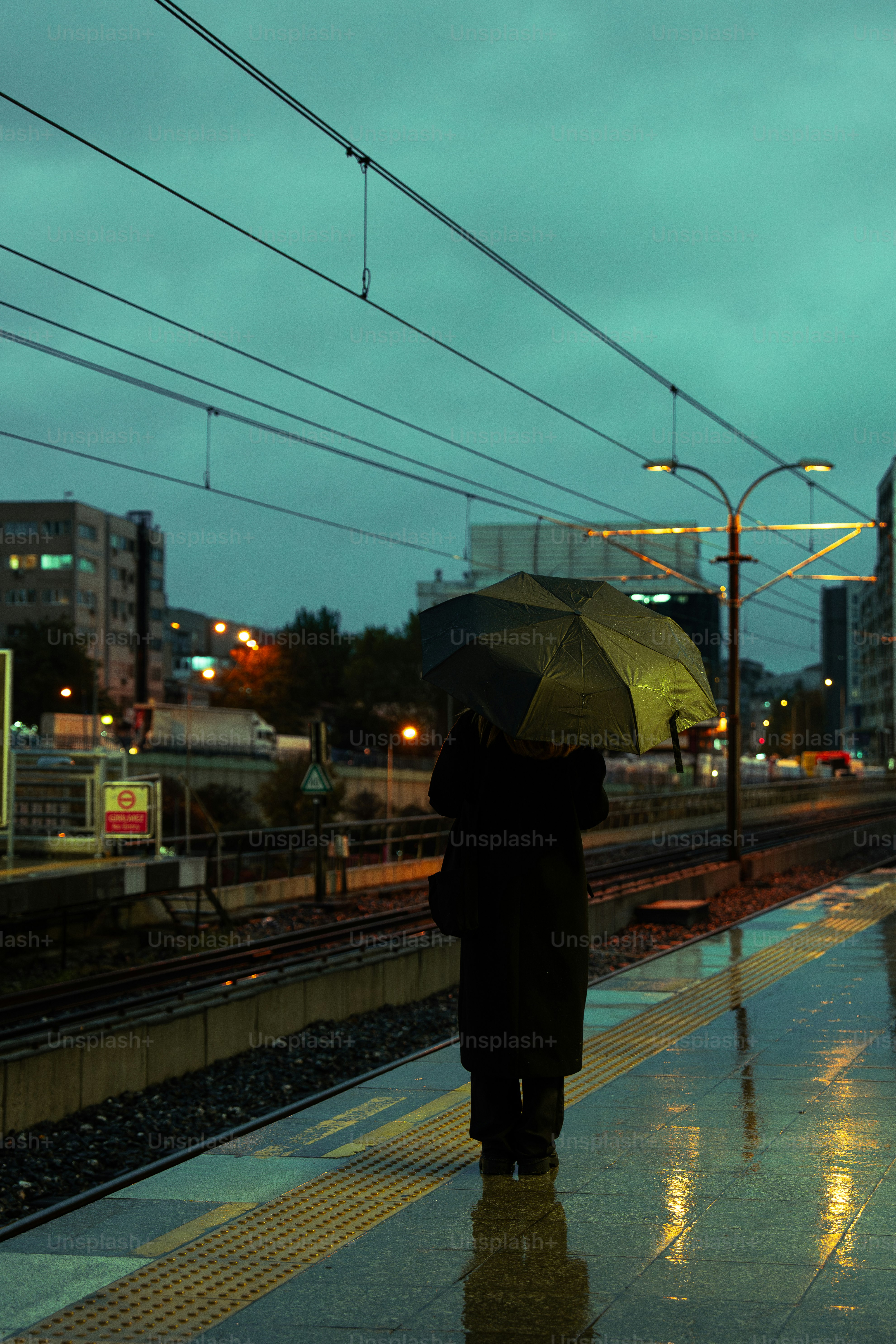 Une personne avec un parapluie attendant un train