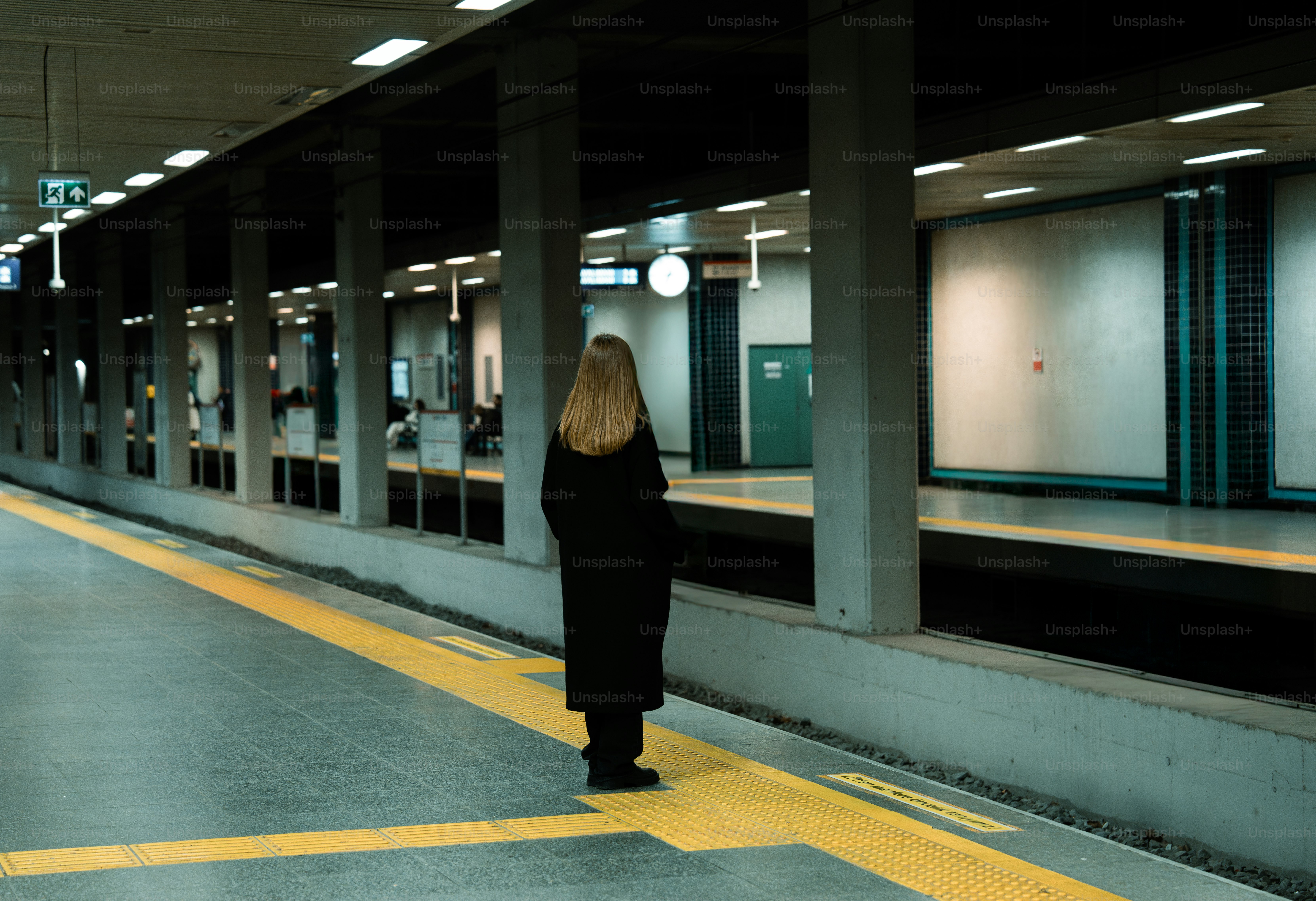 A woman standing in a subway station waiting for a train