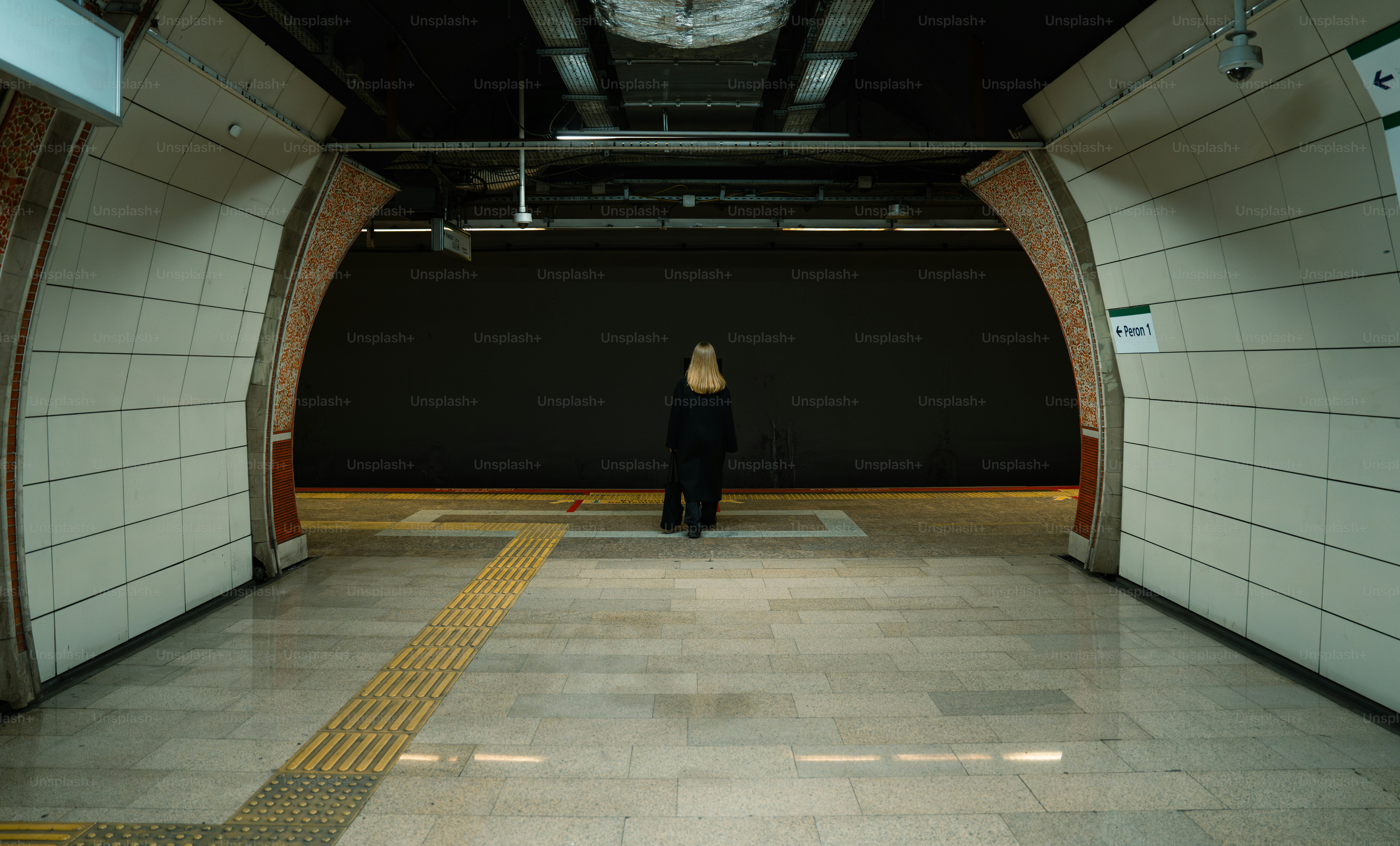 A woman standing in a tunnel with a clock on the wall
