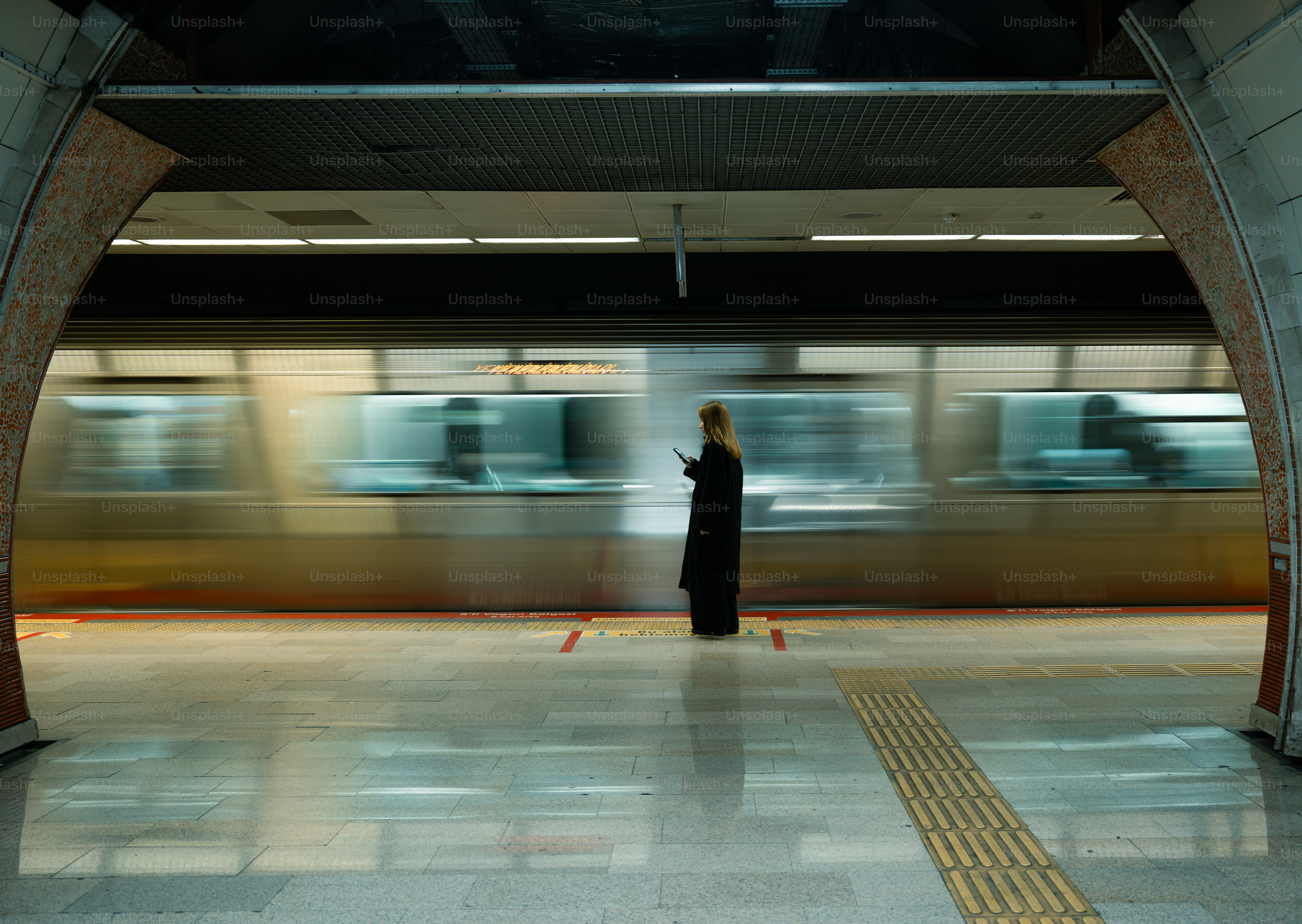 電車が通り過ぎる駅に立つ女性