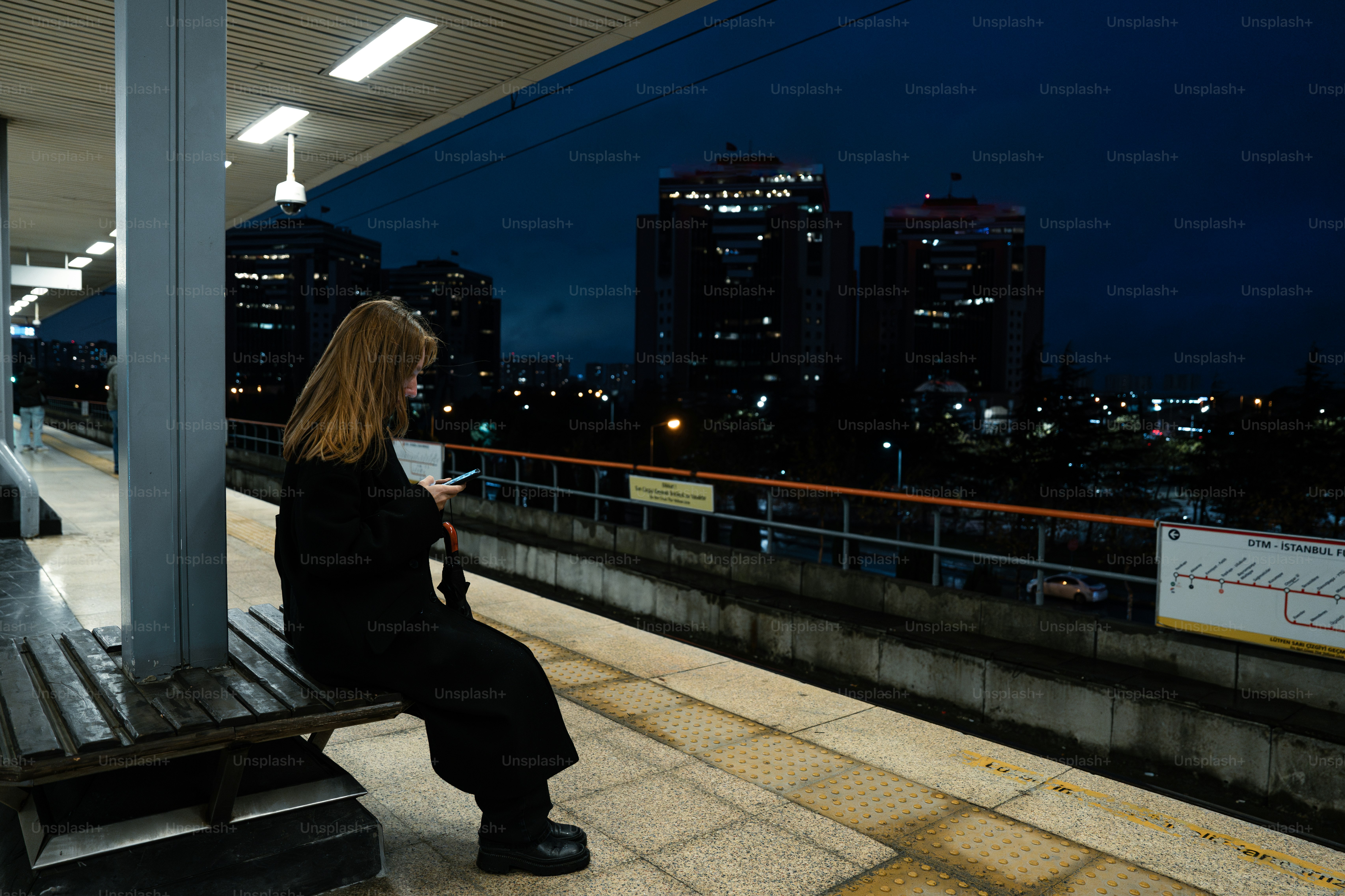 A woman sitting on a bench at a train station