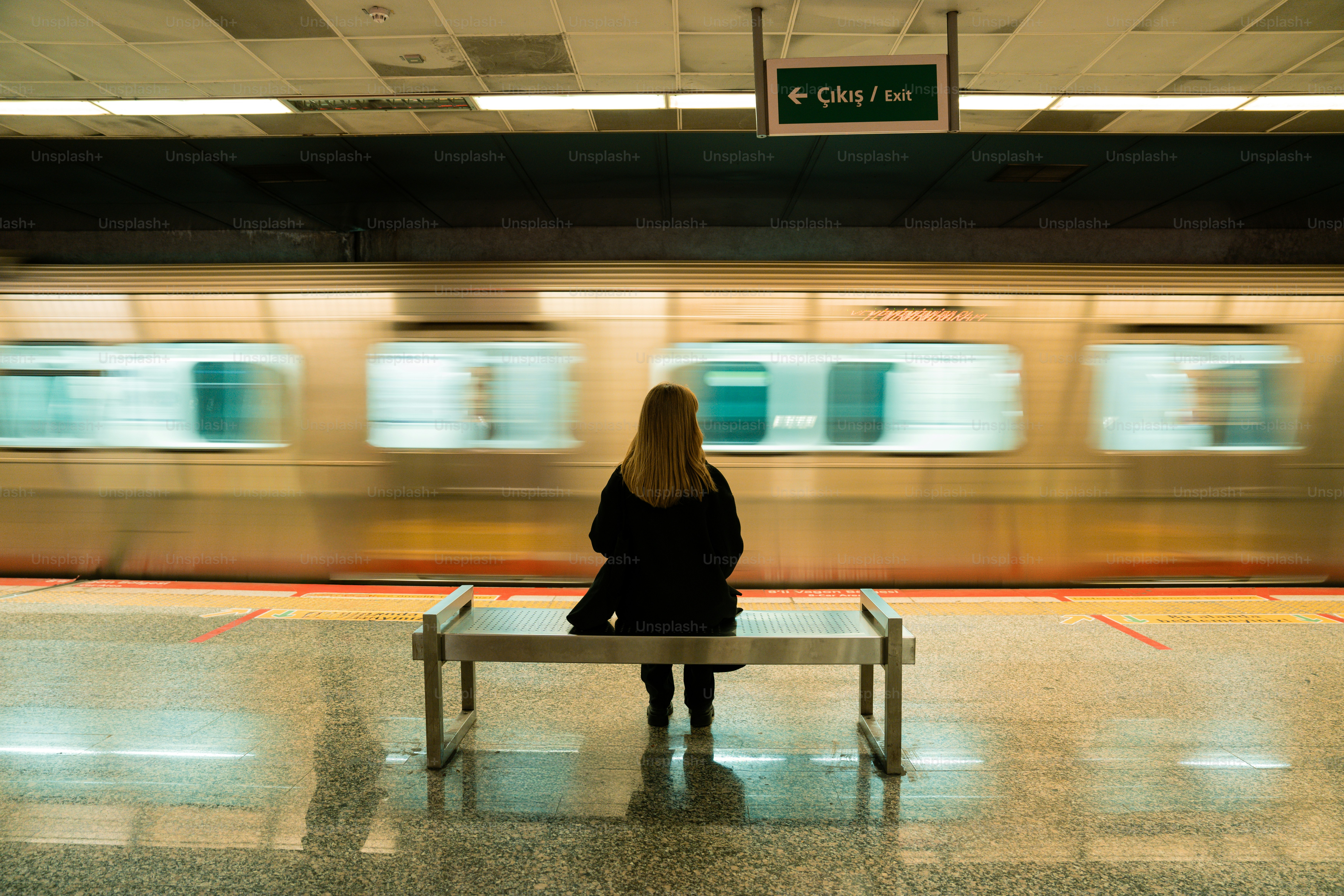 A woman sitting on a bench in a train station