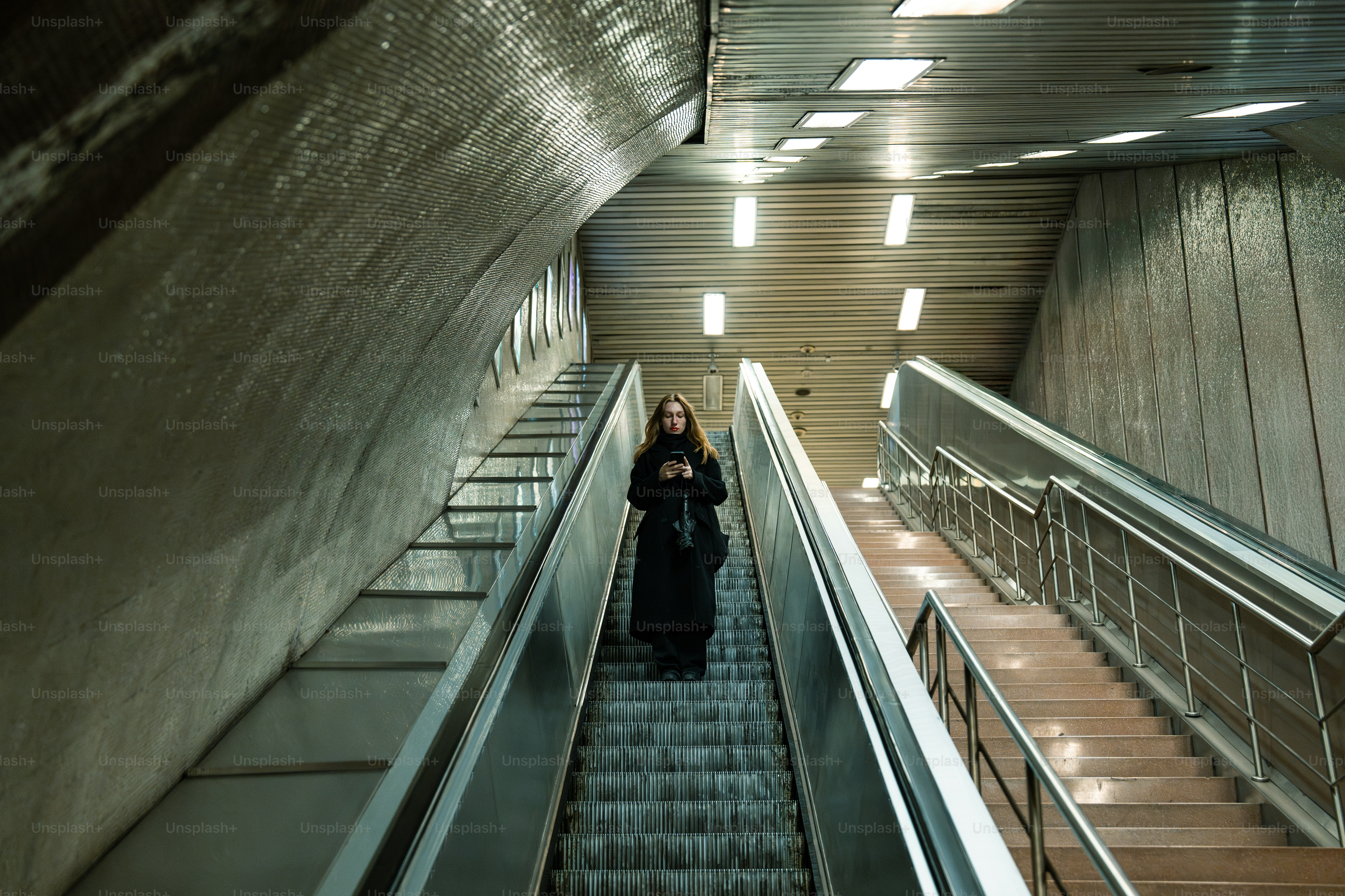 A woman is walking down an escalator in a building