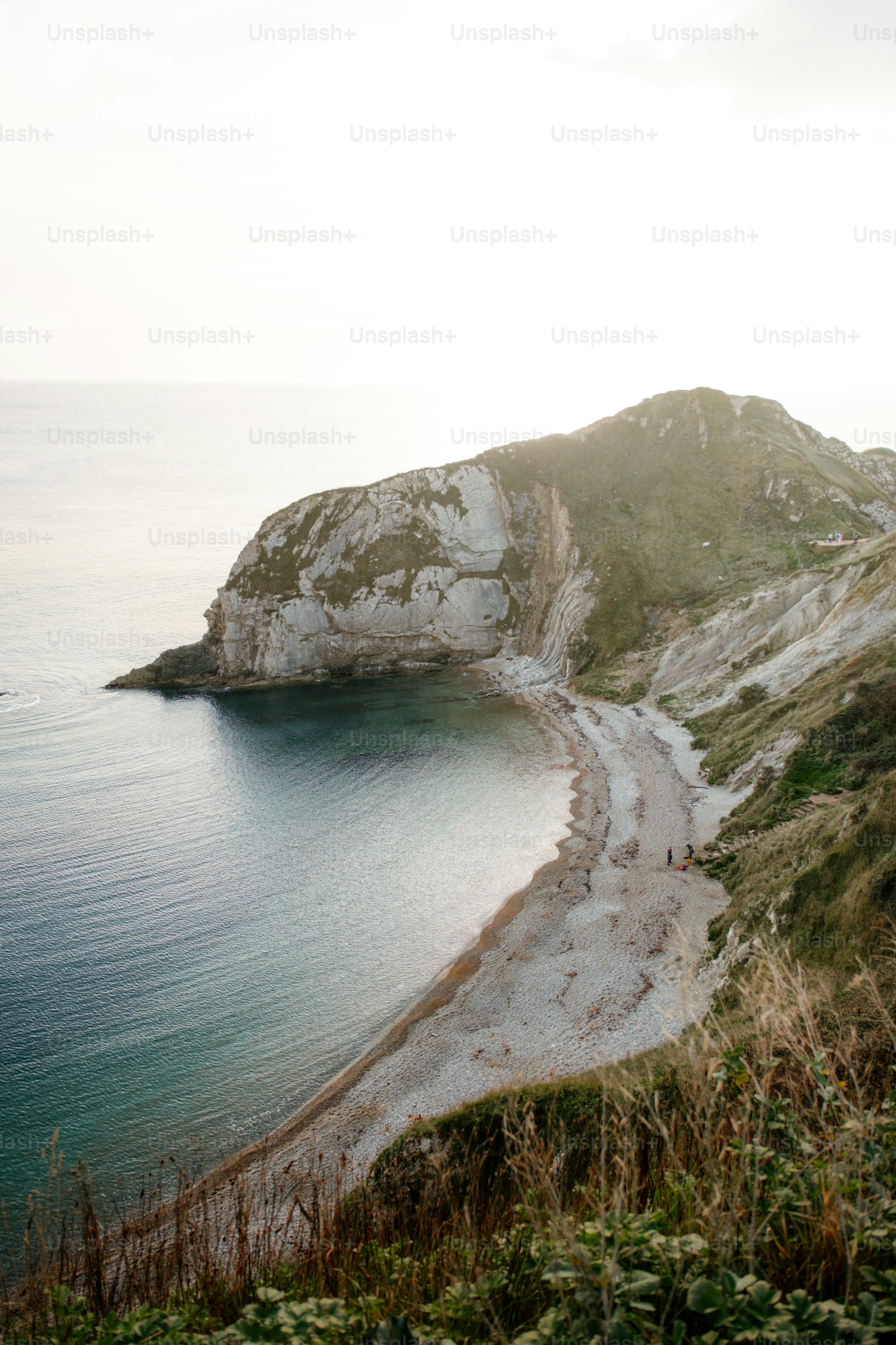 A large body of water sitting next to a lush green hillside