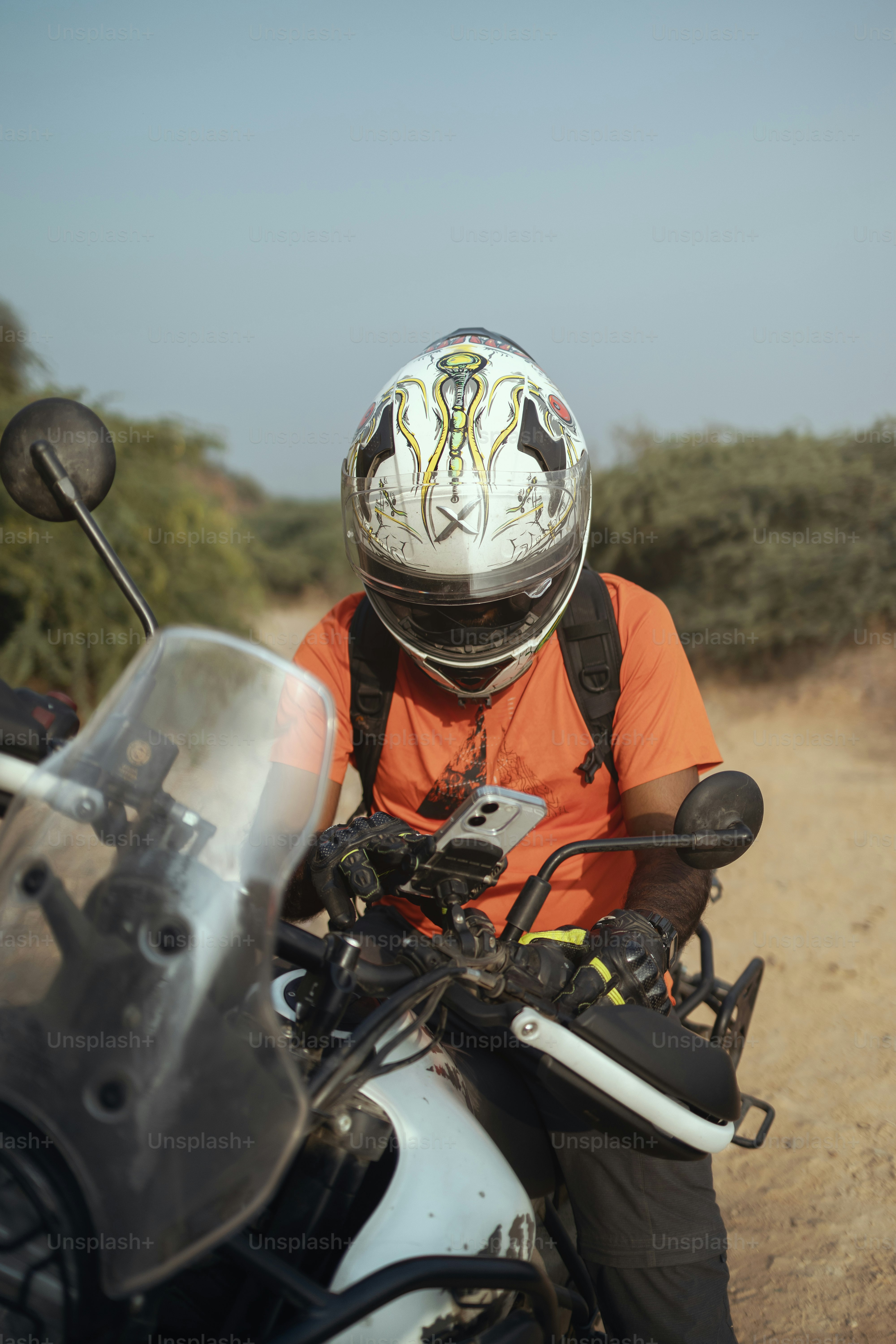 A man riding on the back of a motorcycle down a dirt road