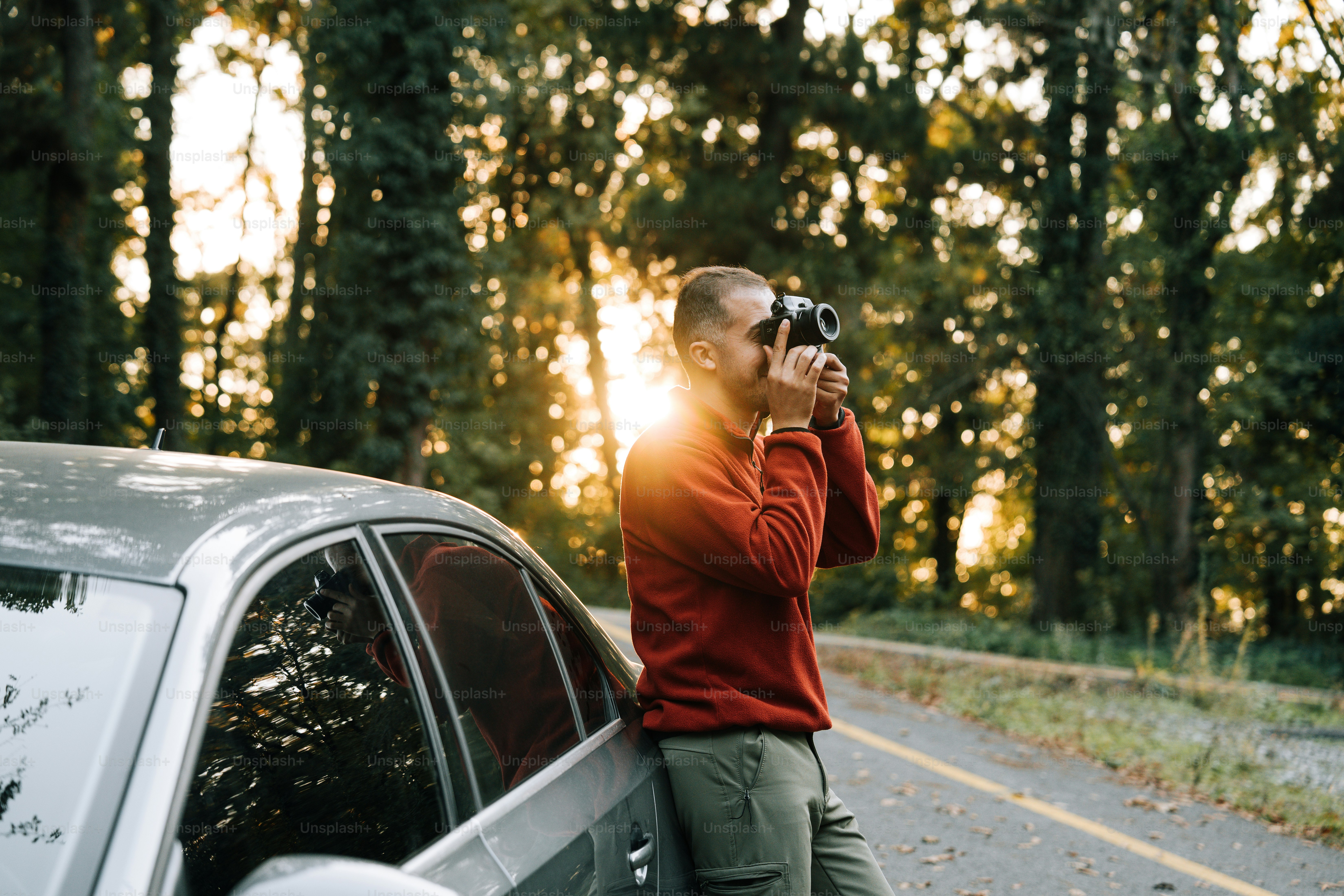 道路脇で車の写真を撮っている男性