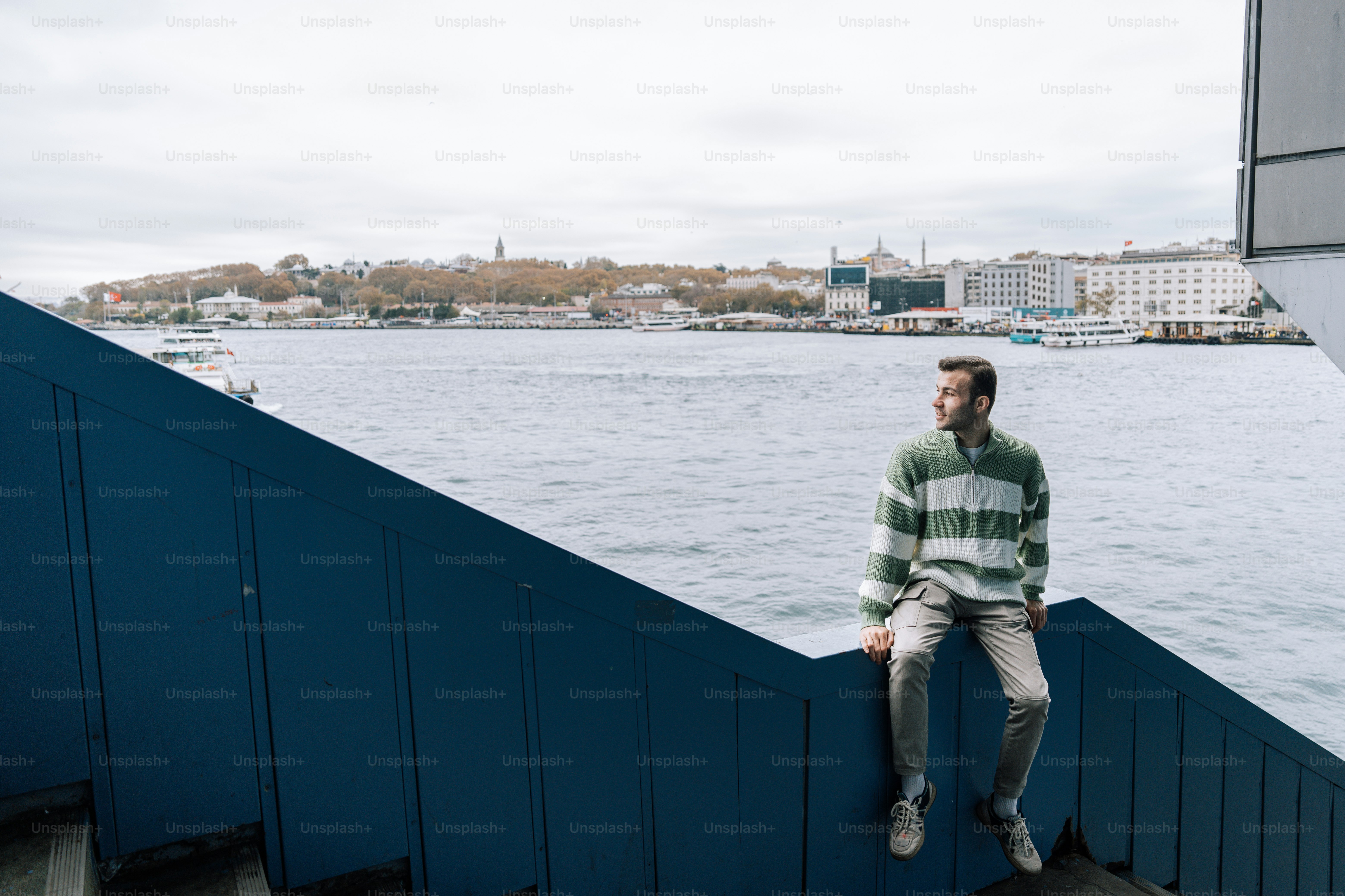 A man sitting on a wall next to a body of water