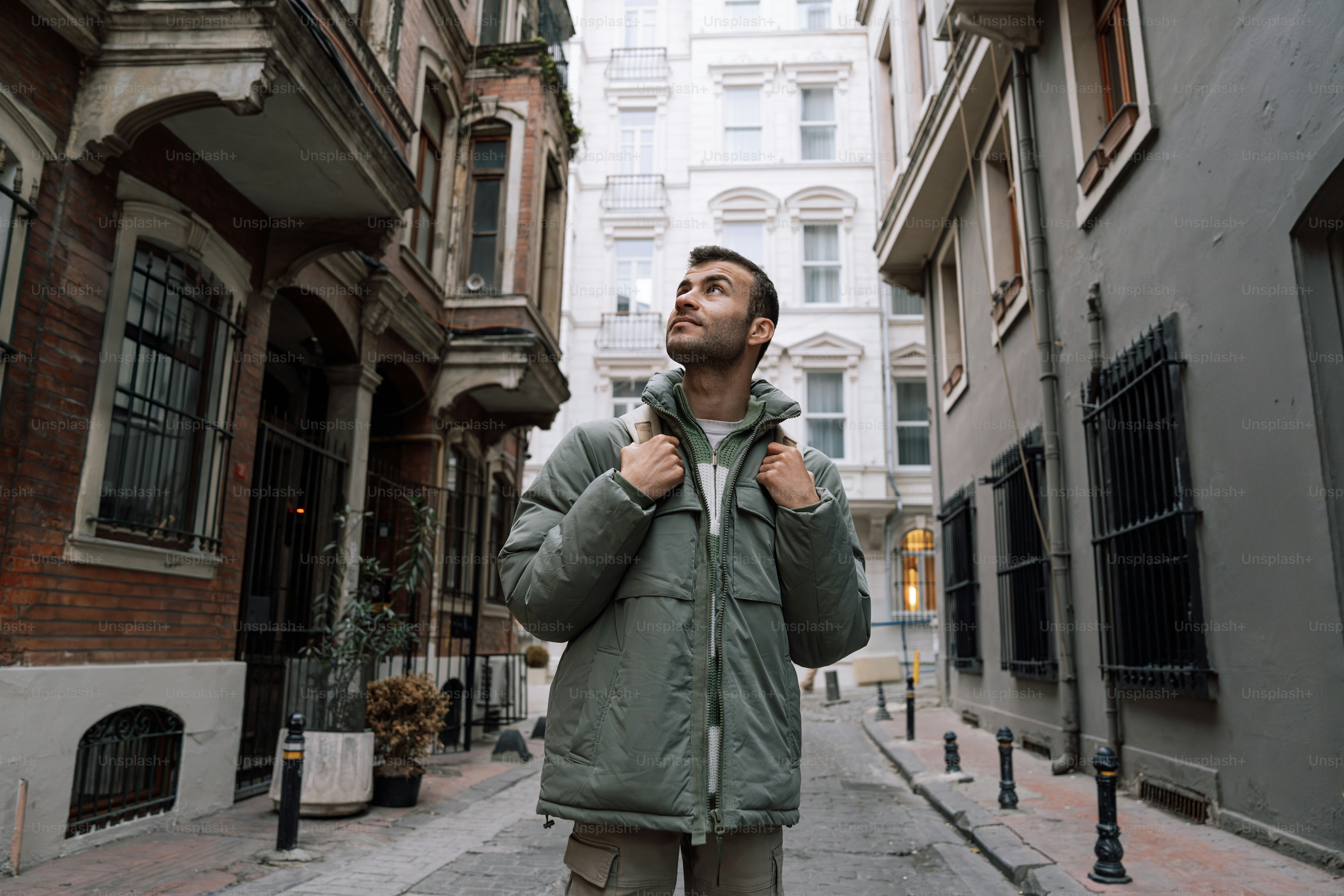 A man sitting on a bench in front of a building photo – Green Image on ...