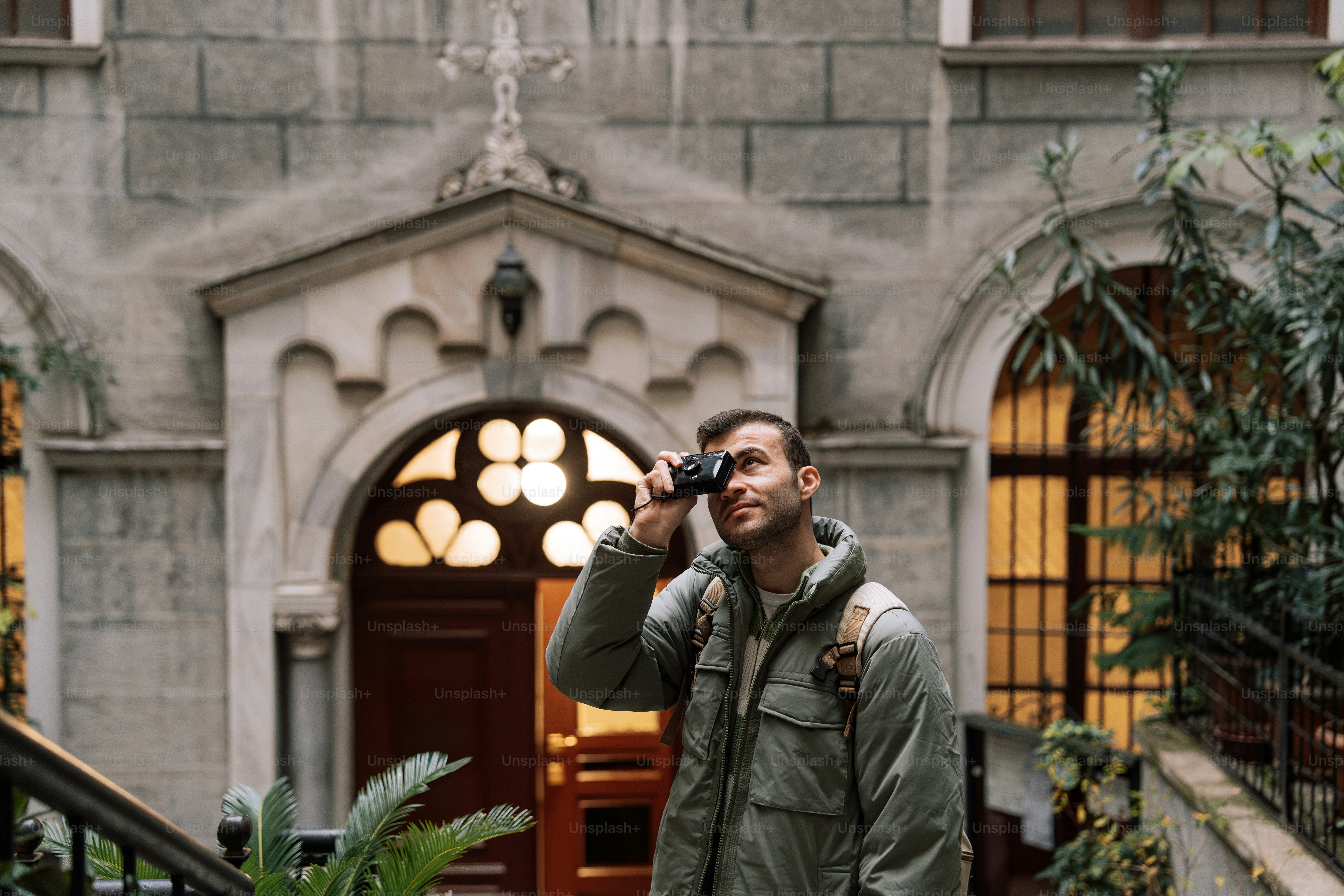 A man sitting on a bench in front of a building photo – Green Image on ...
