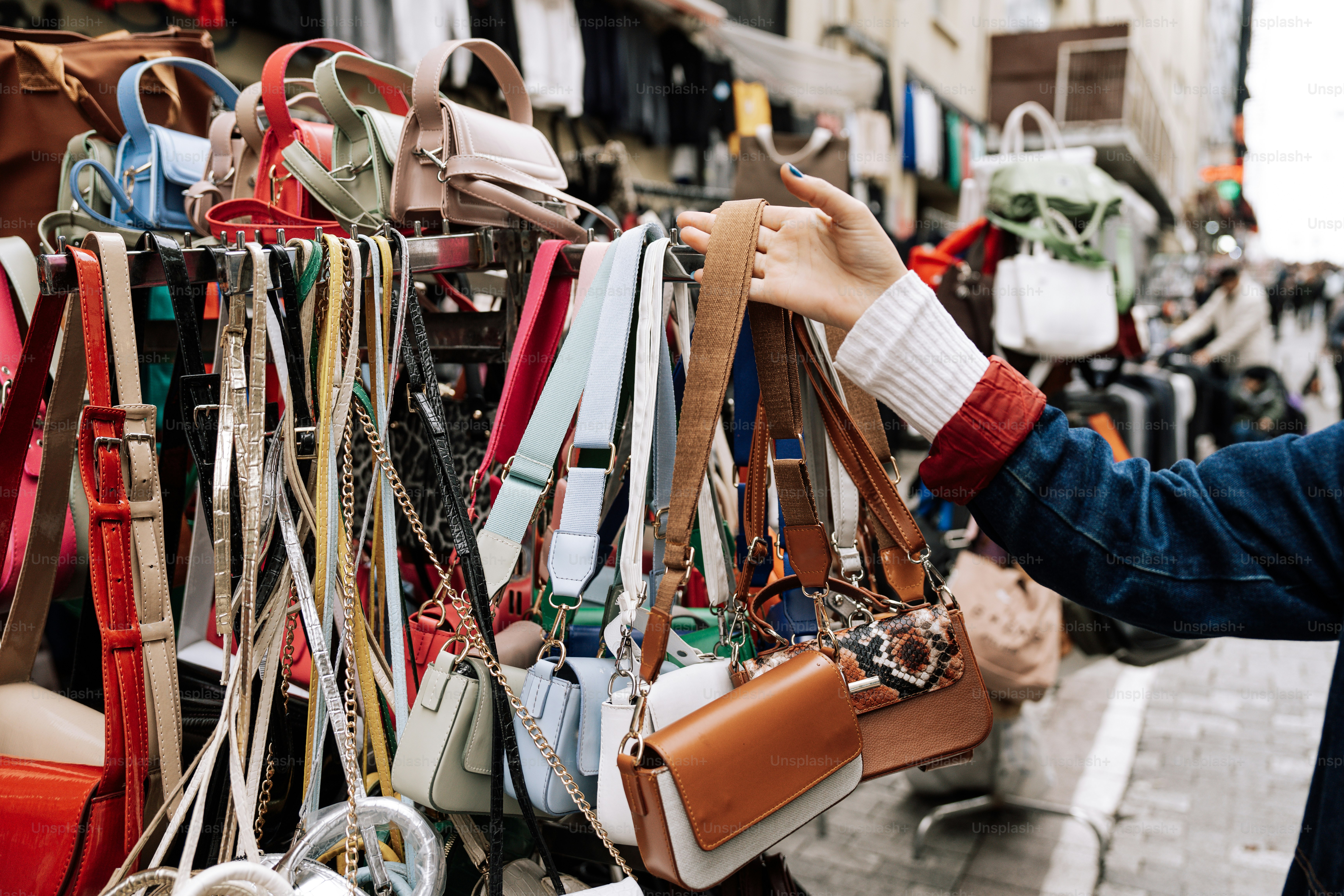 A woman is looking at a rack of purses