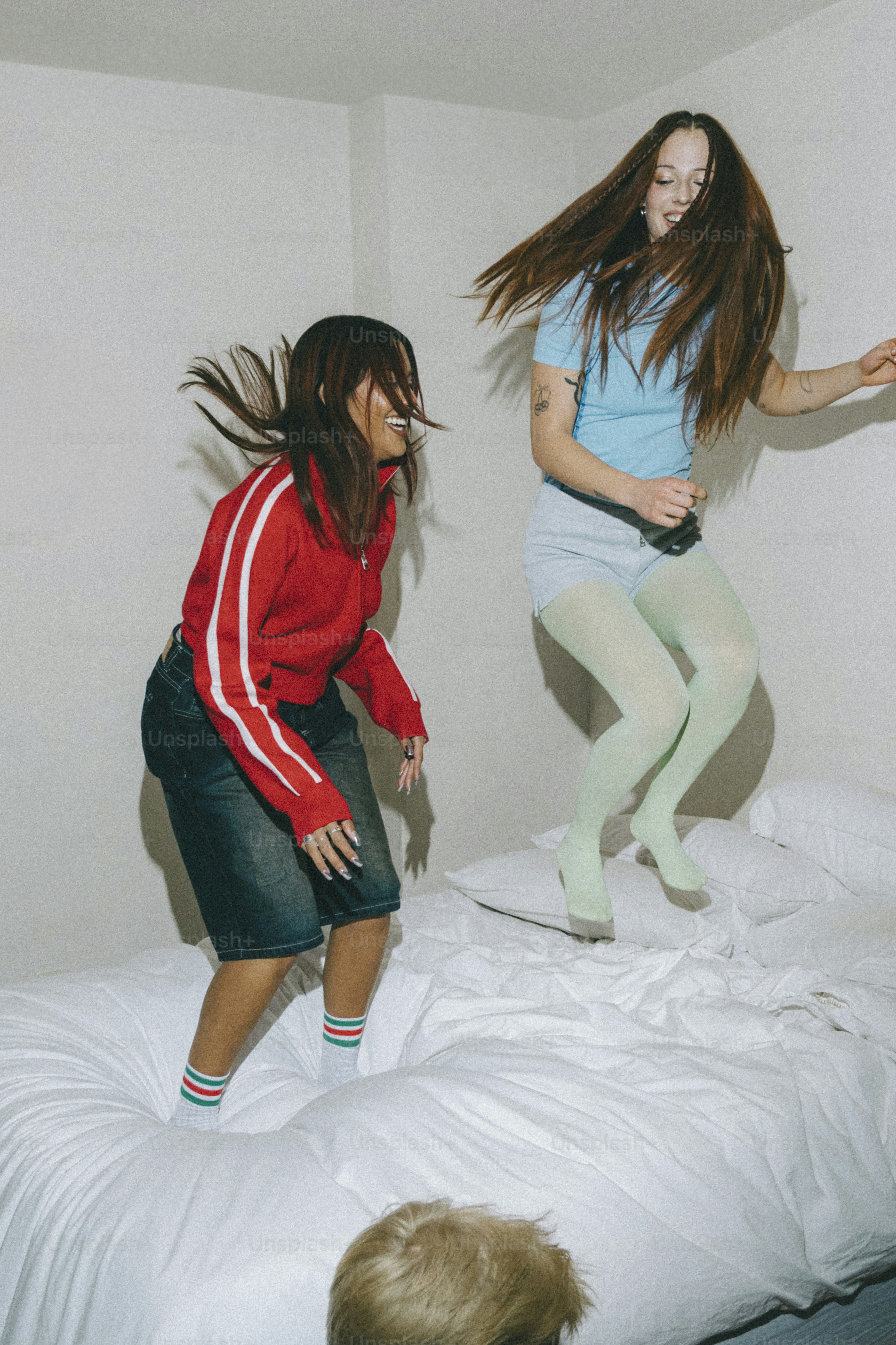 Two girls jumping on a bed in a room