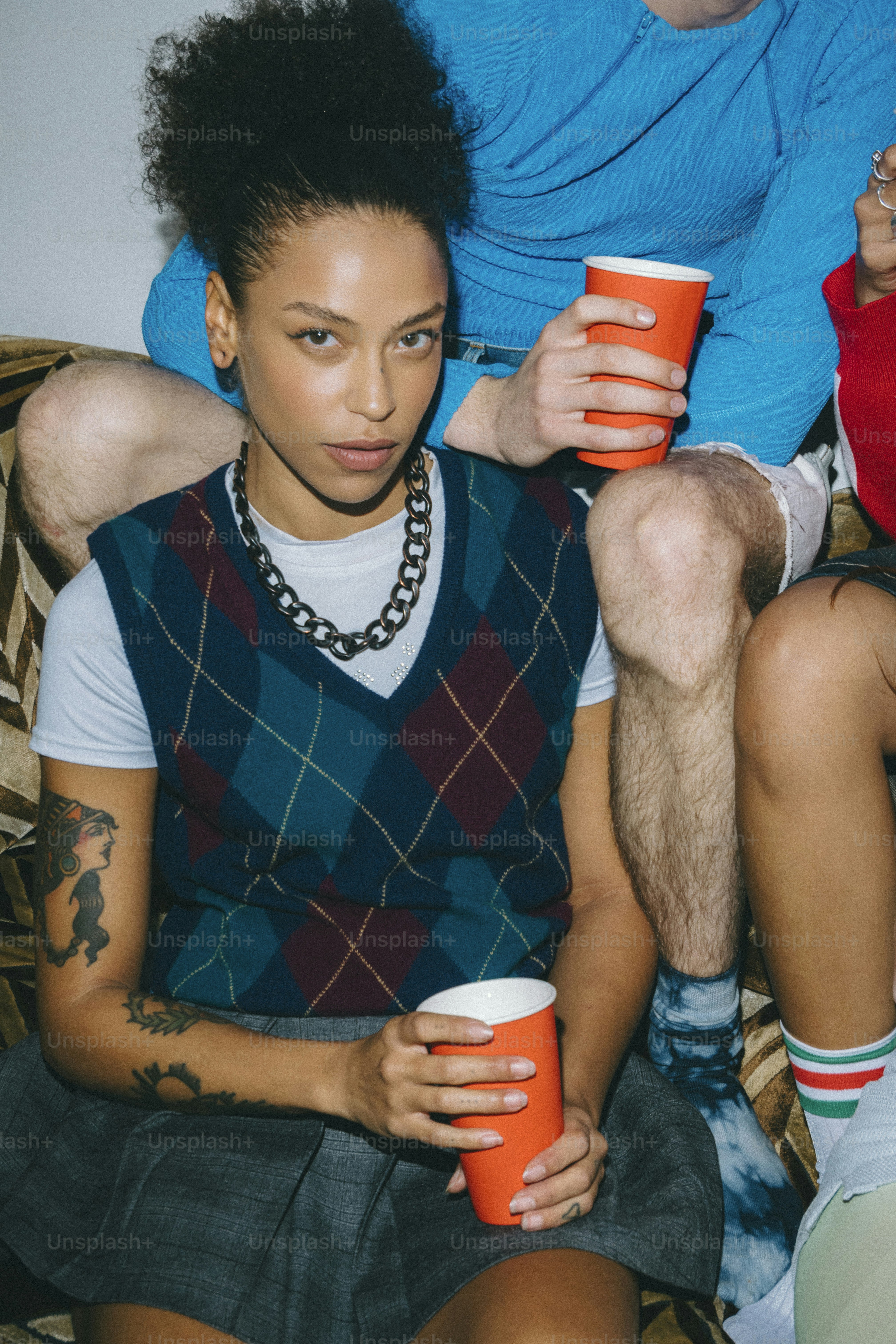 A man and a woman sitting on a couch holding coffee cups
