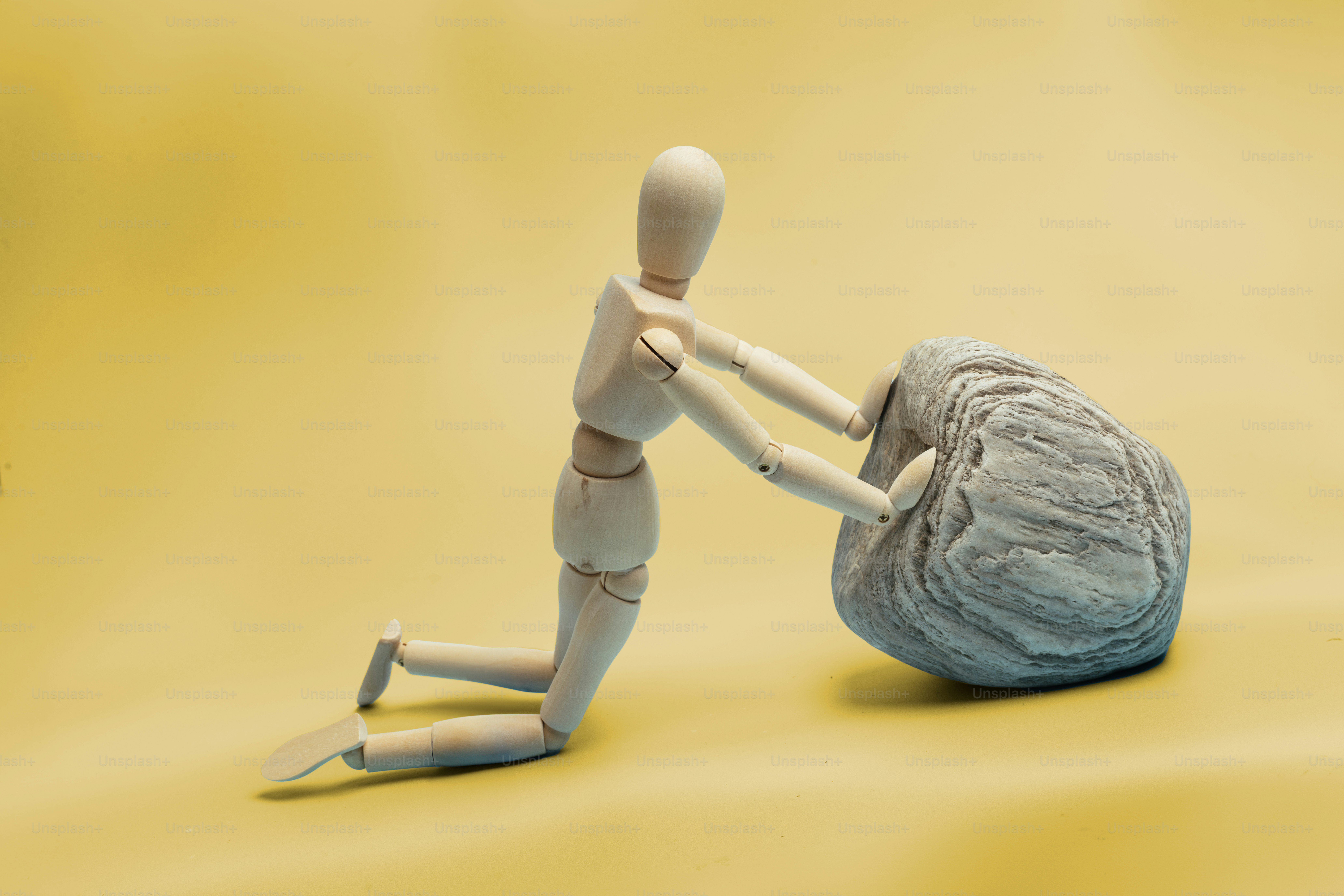 Una piccola bambola sta spingendo una grande roccia