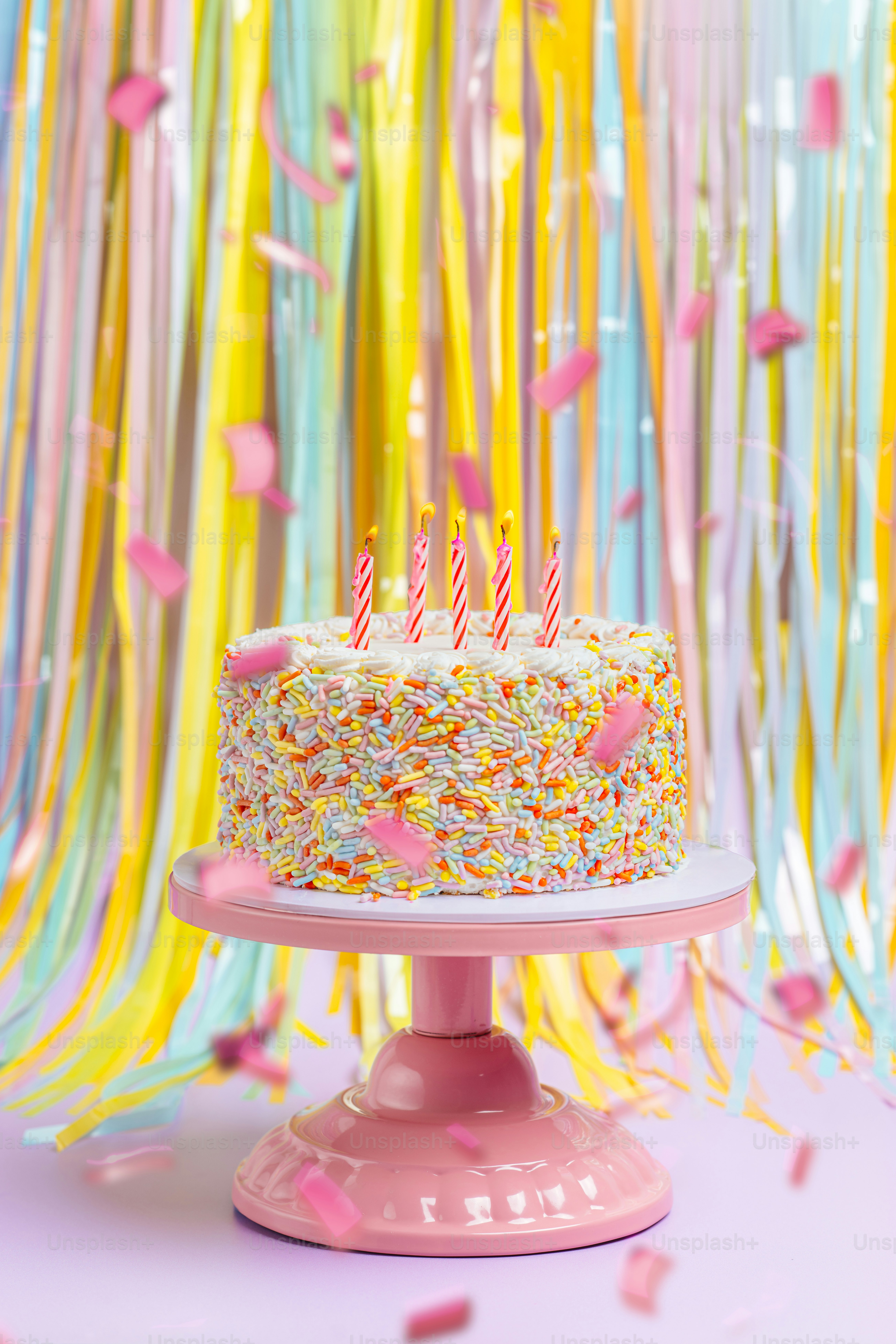 Una torta di compleanno seduta sopra un piatto da torta rosa