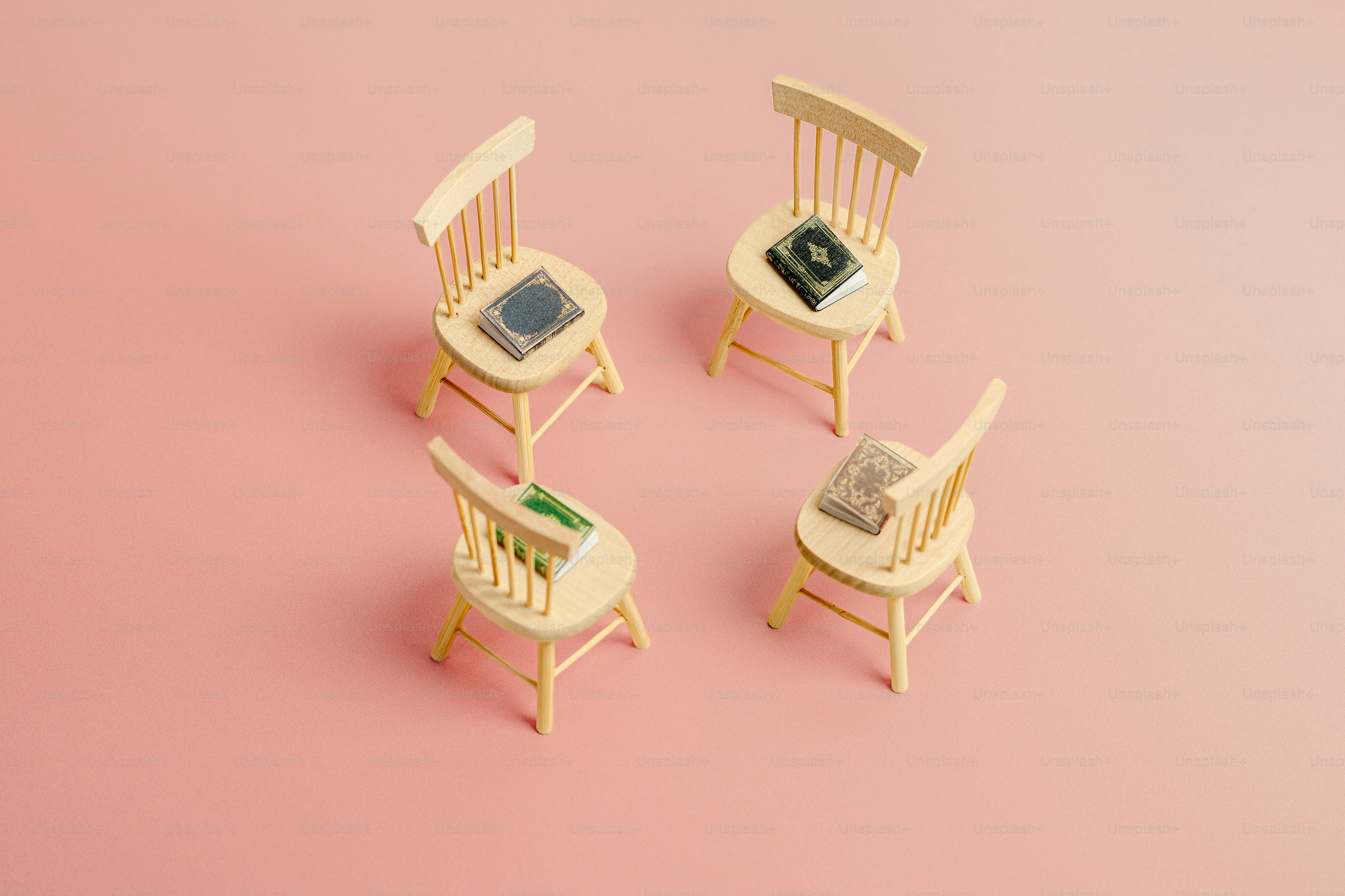 분홍색 배경에 미니어처 의자 3개와 테이블