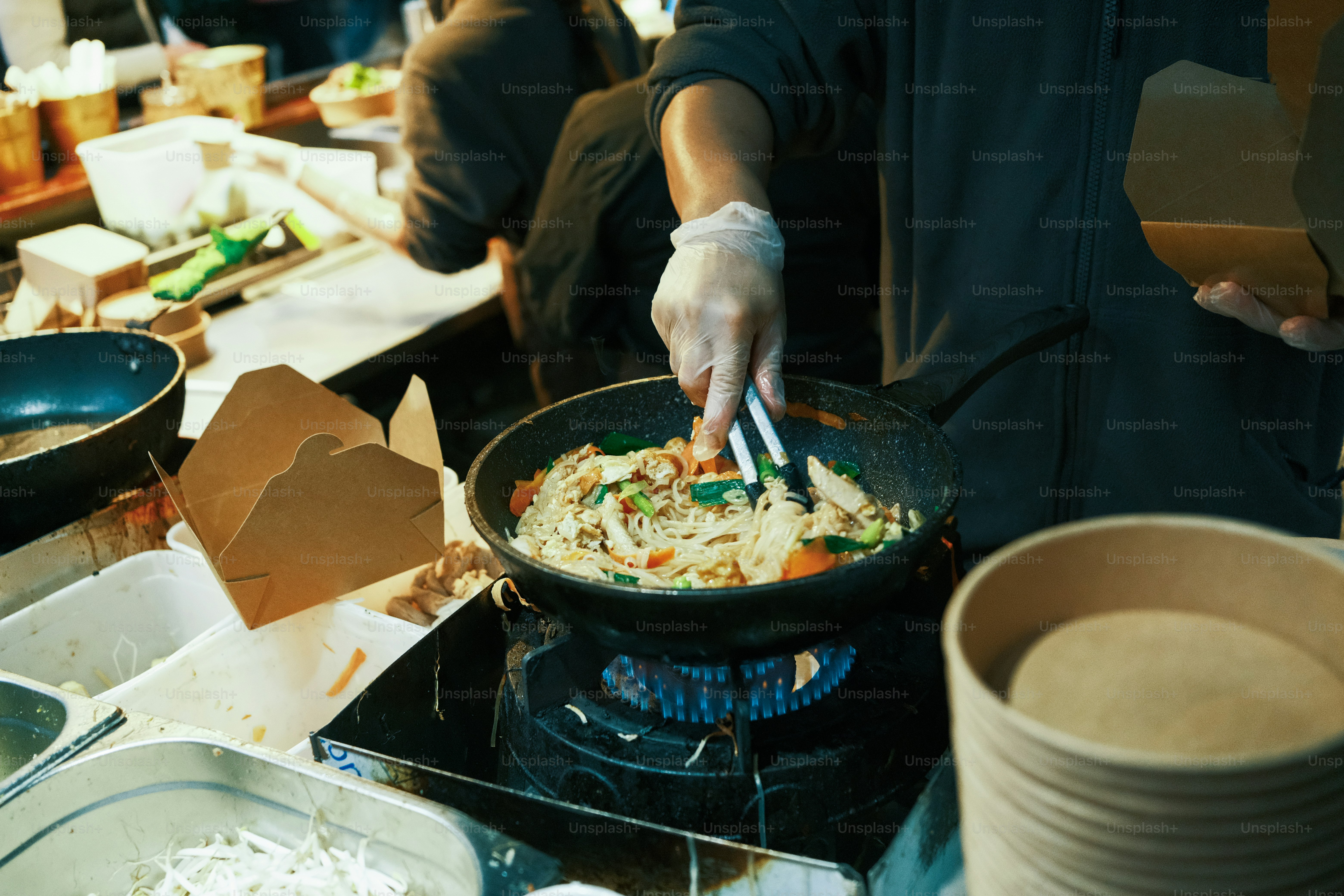 A person cooking food in a wok on top of a stove