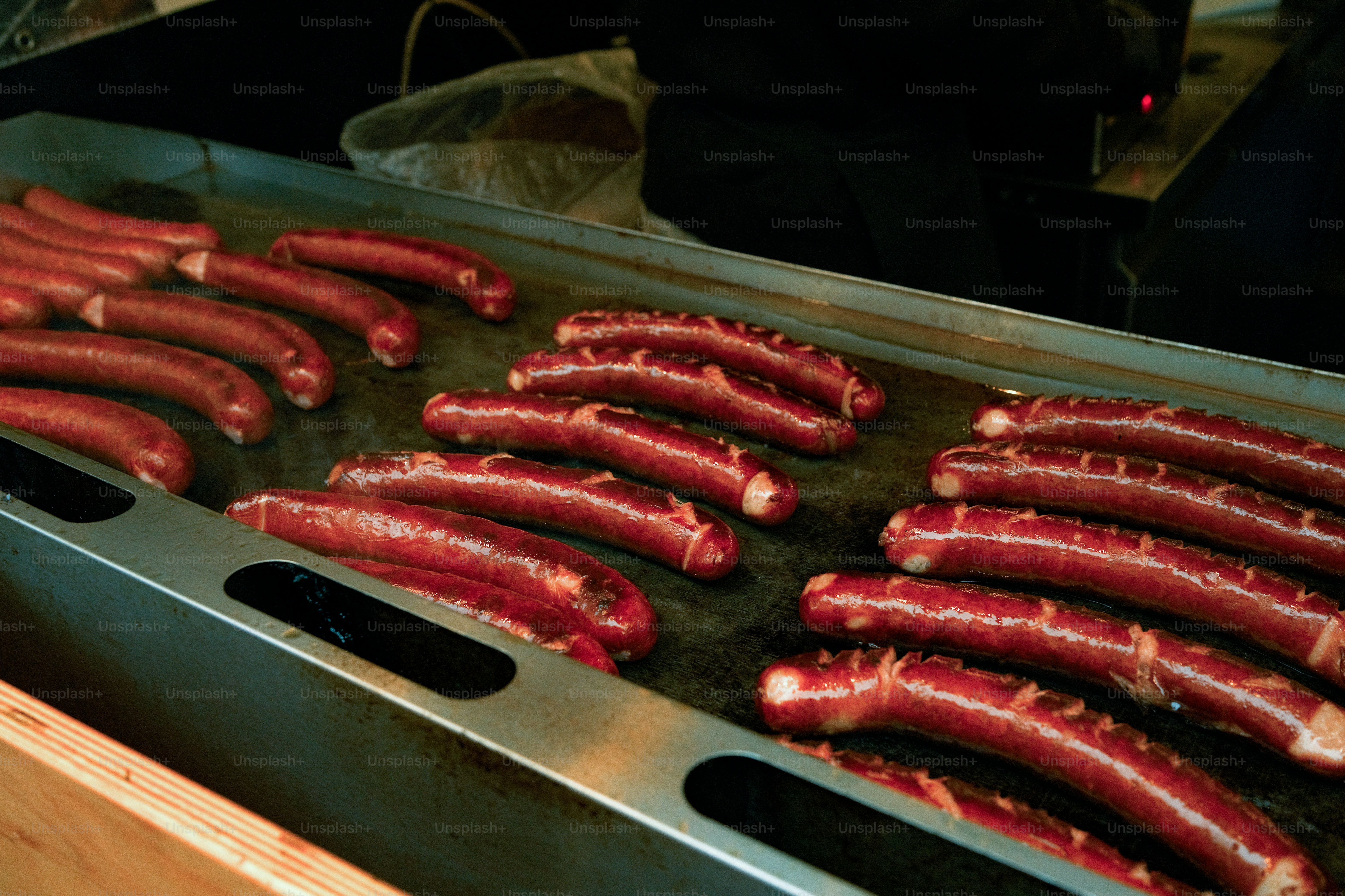 A bunch of sausages are being cooked on a grill