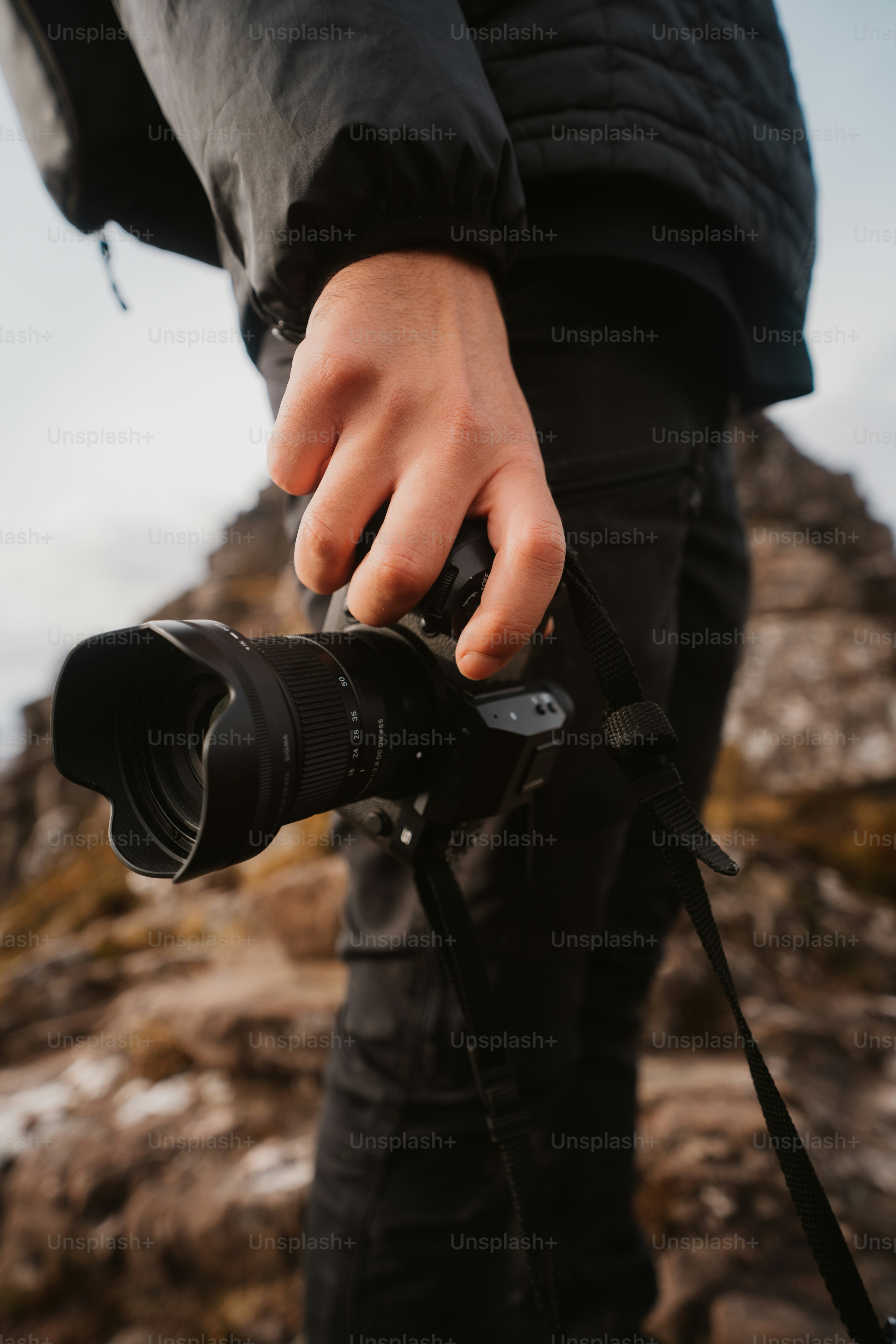 A person holding a camera on top of a mountain