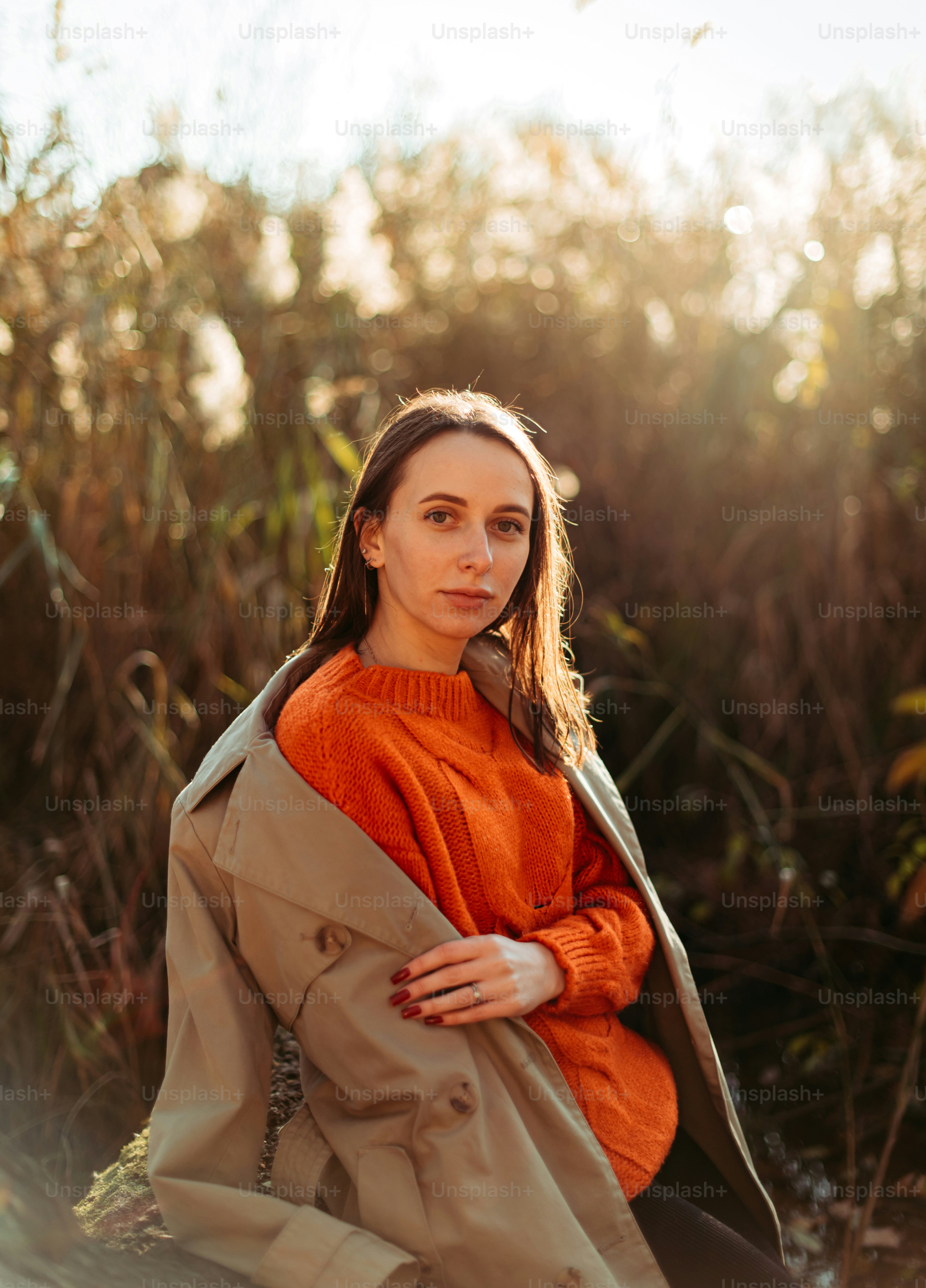 A woman sitting on the ground in a trench coat