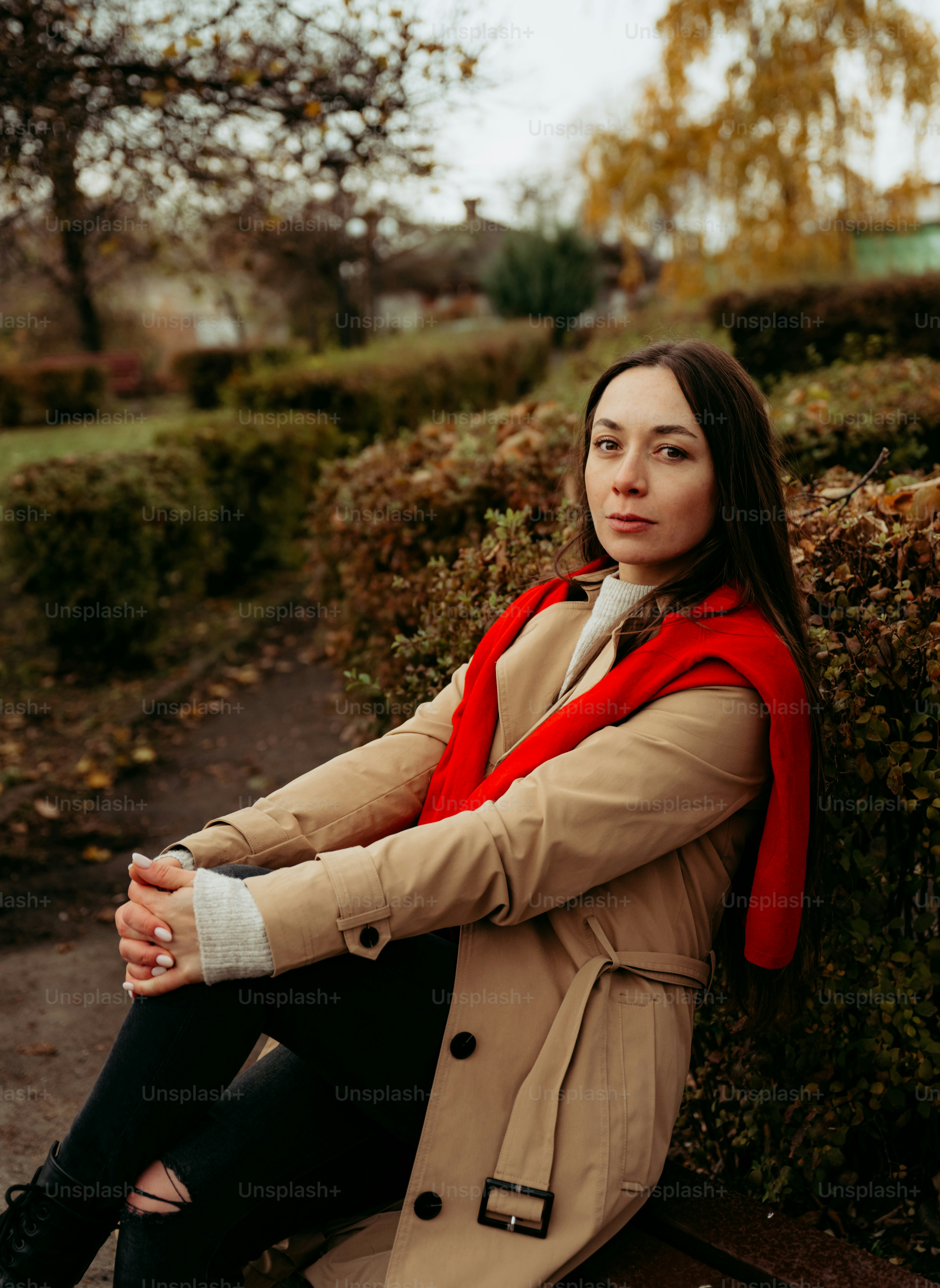 A woman in a trench coat sitting on a bench