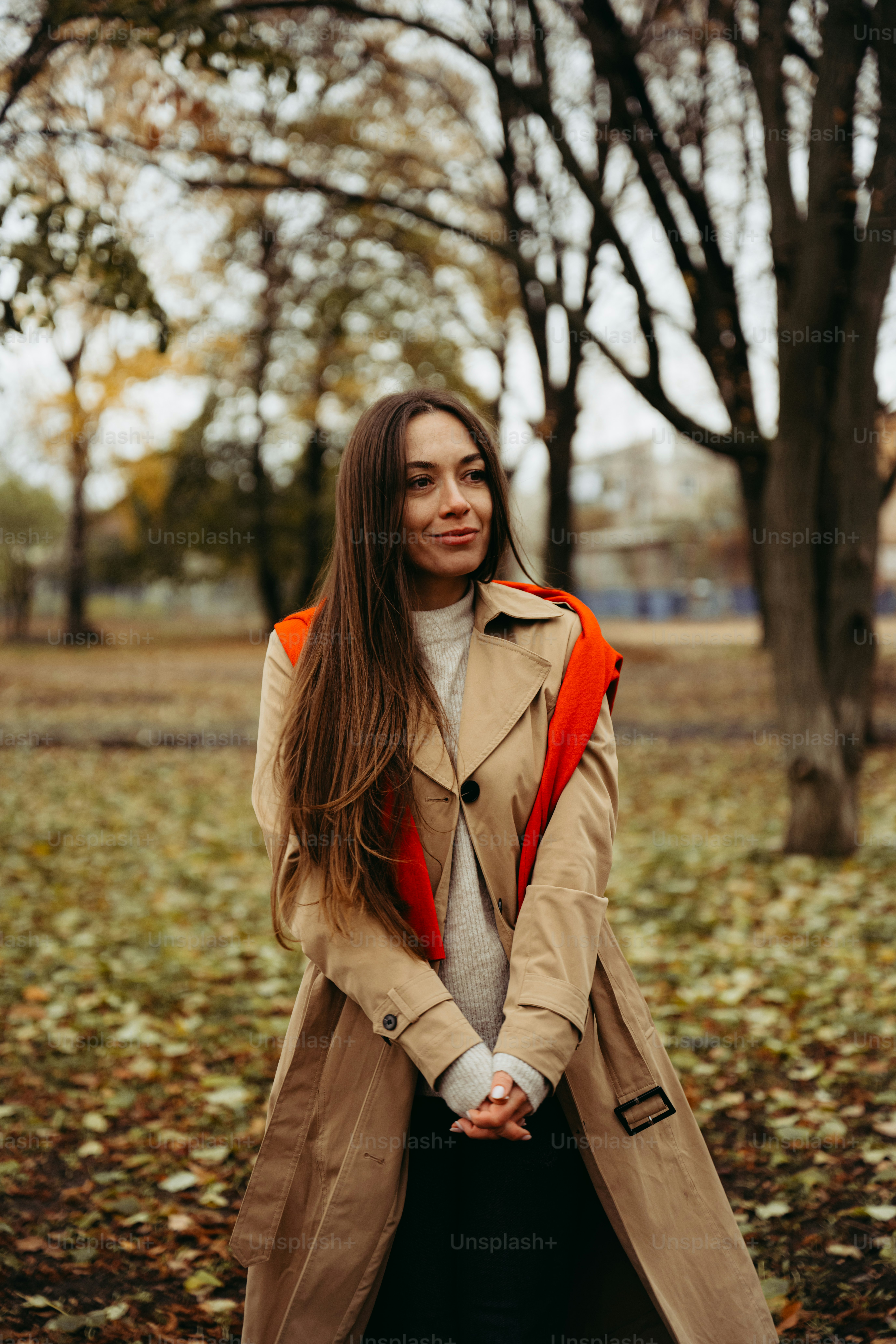 A woman in a trench coat standing in a park