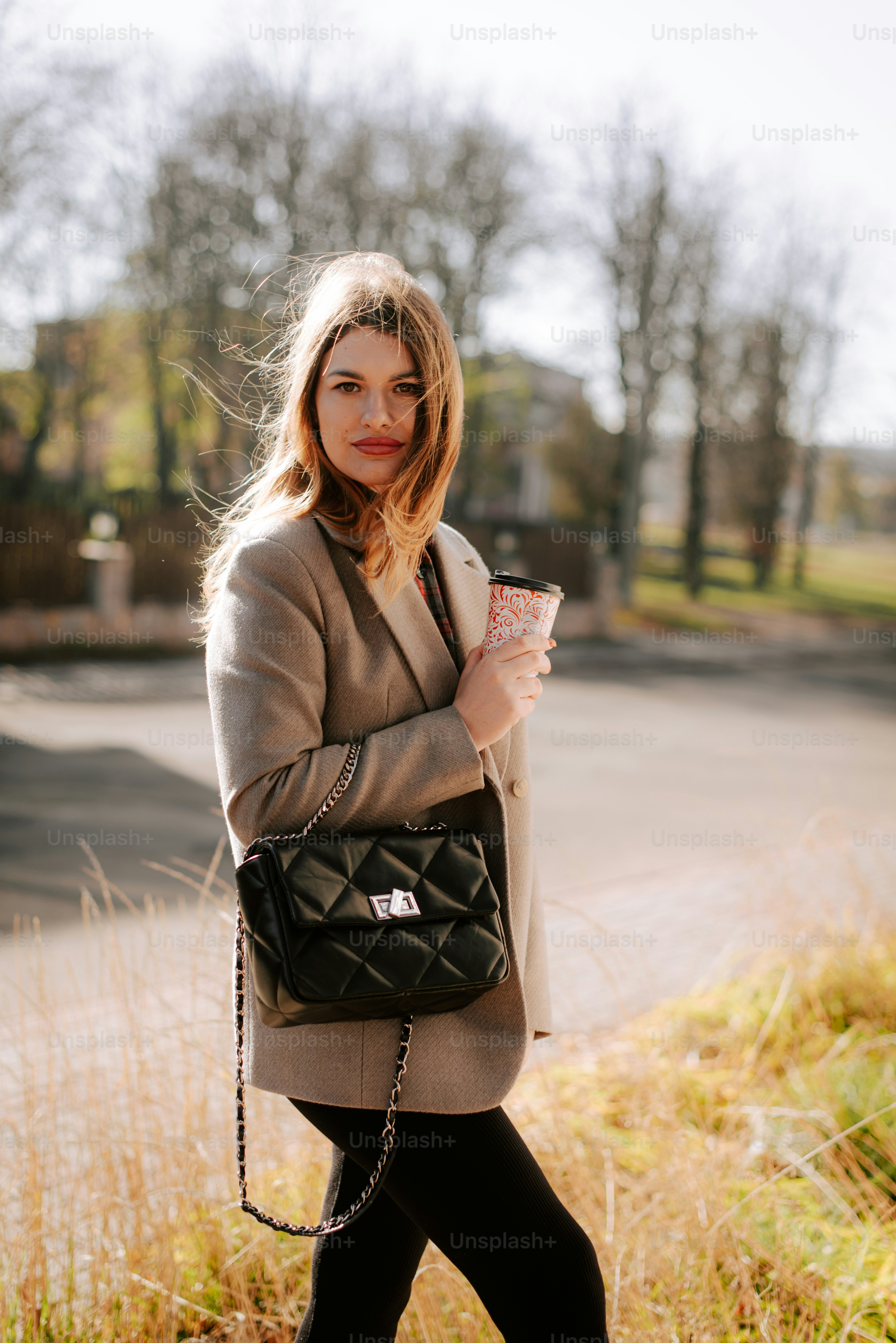 A woman walking down a street holding a black purse