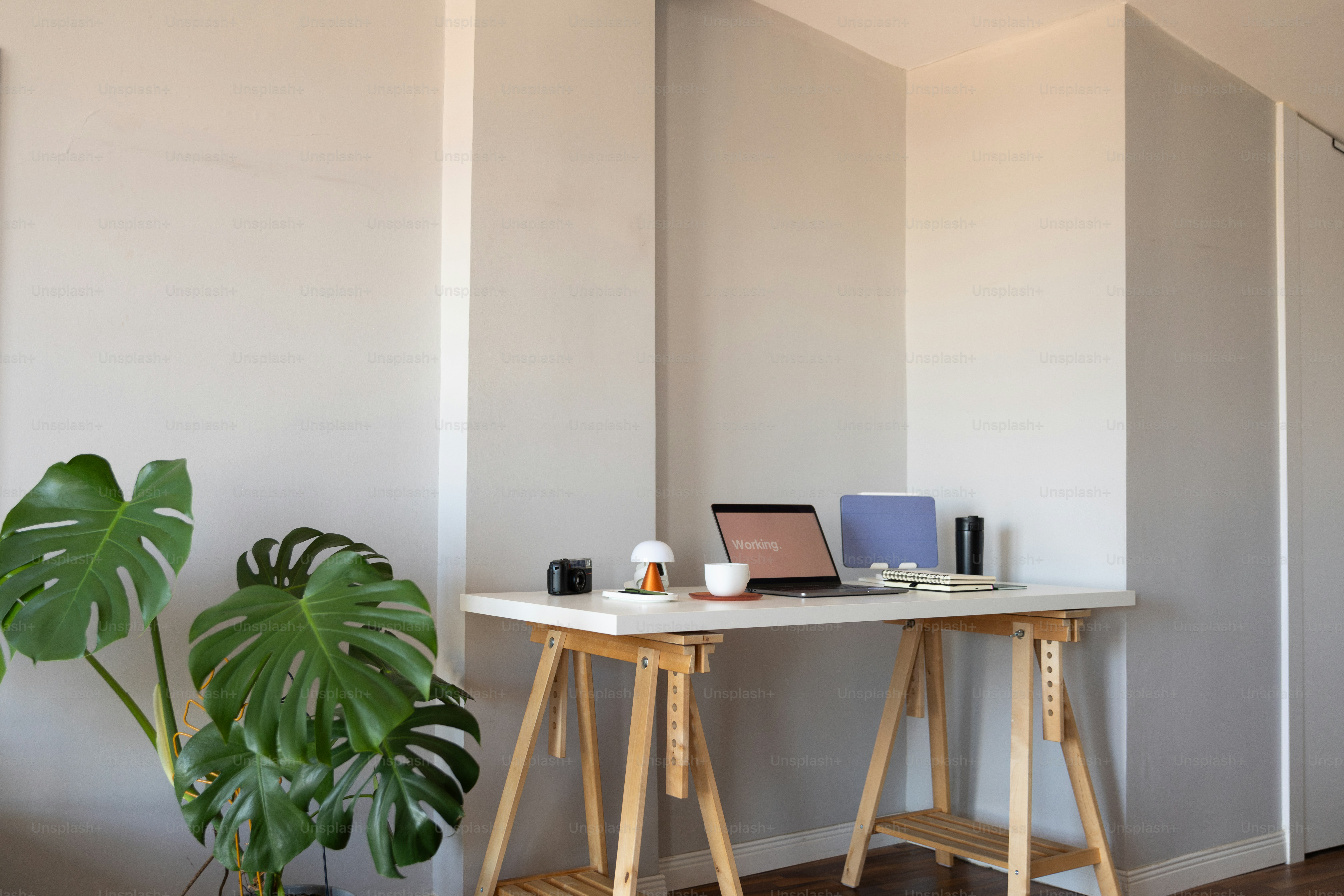 A table with a laptop on top of it next to a potted plant