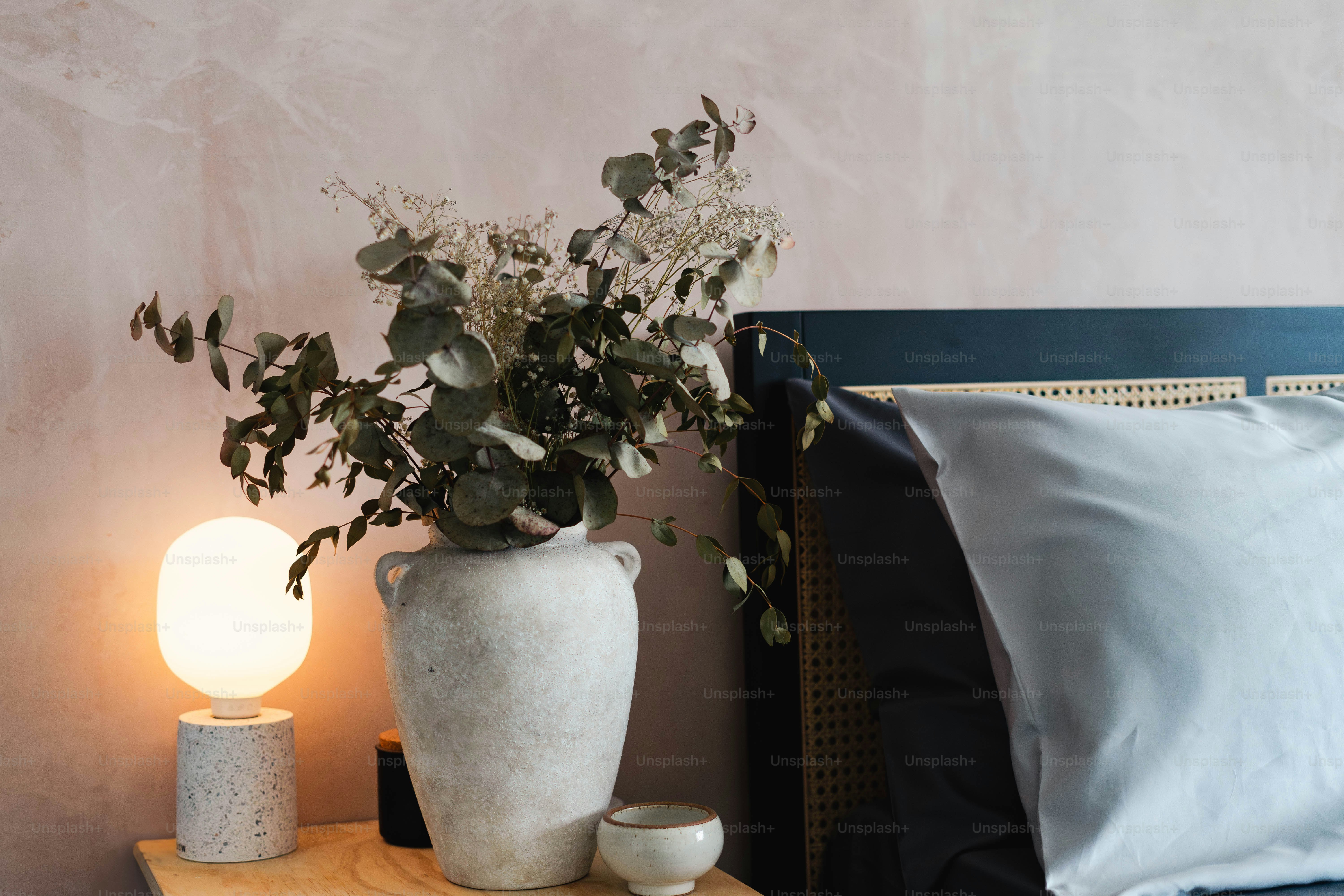 A bed with a night stand and a vase with flowers on it
