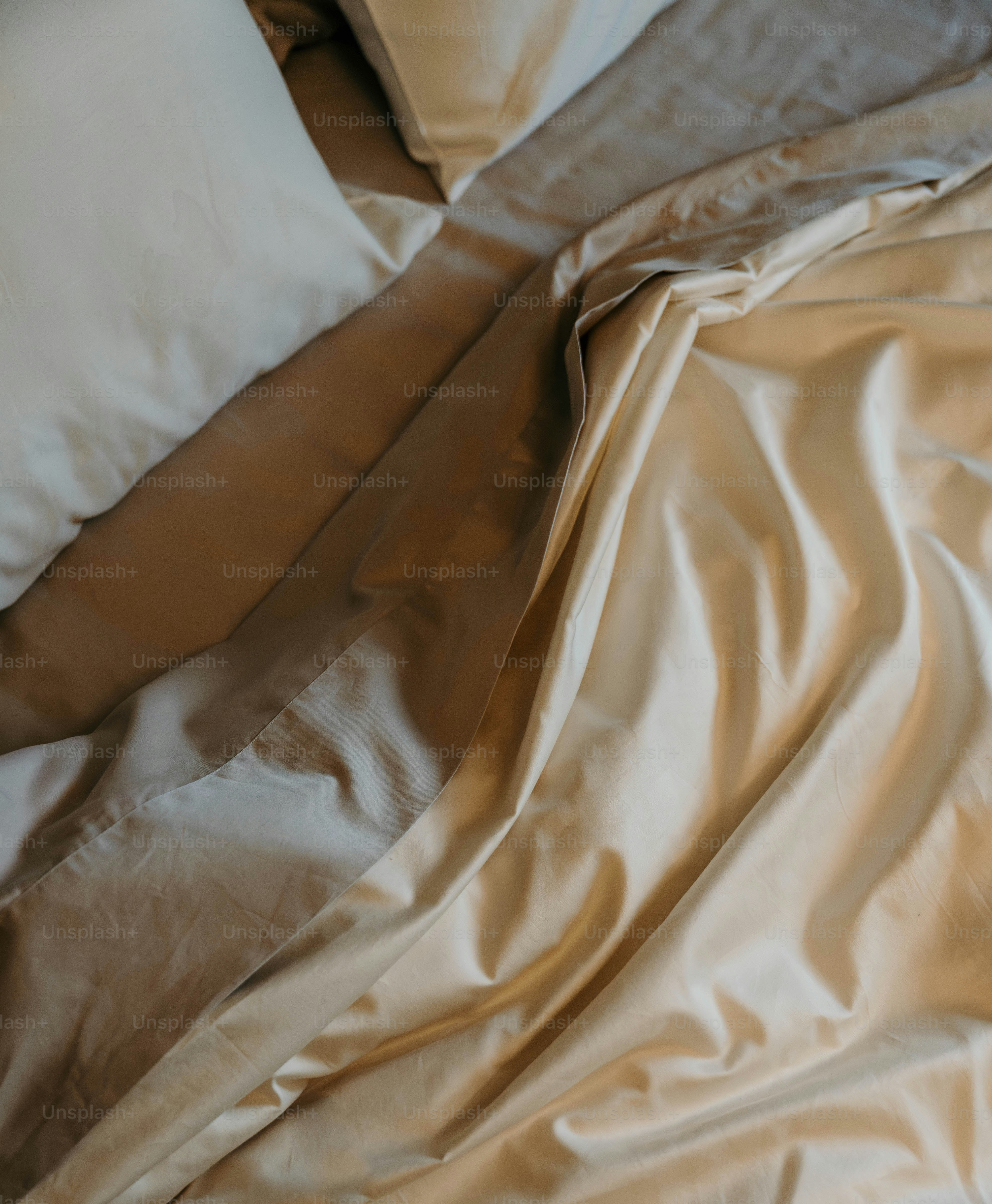 An unmade bed with white sheets and pillows