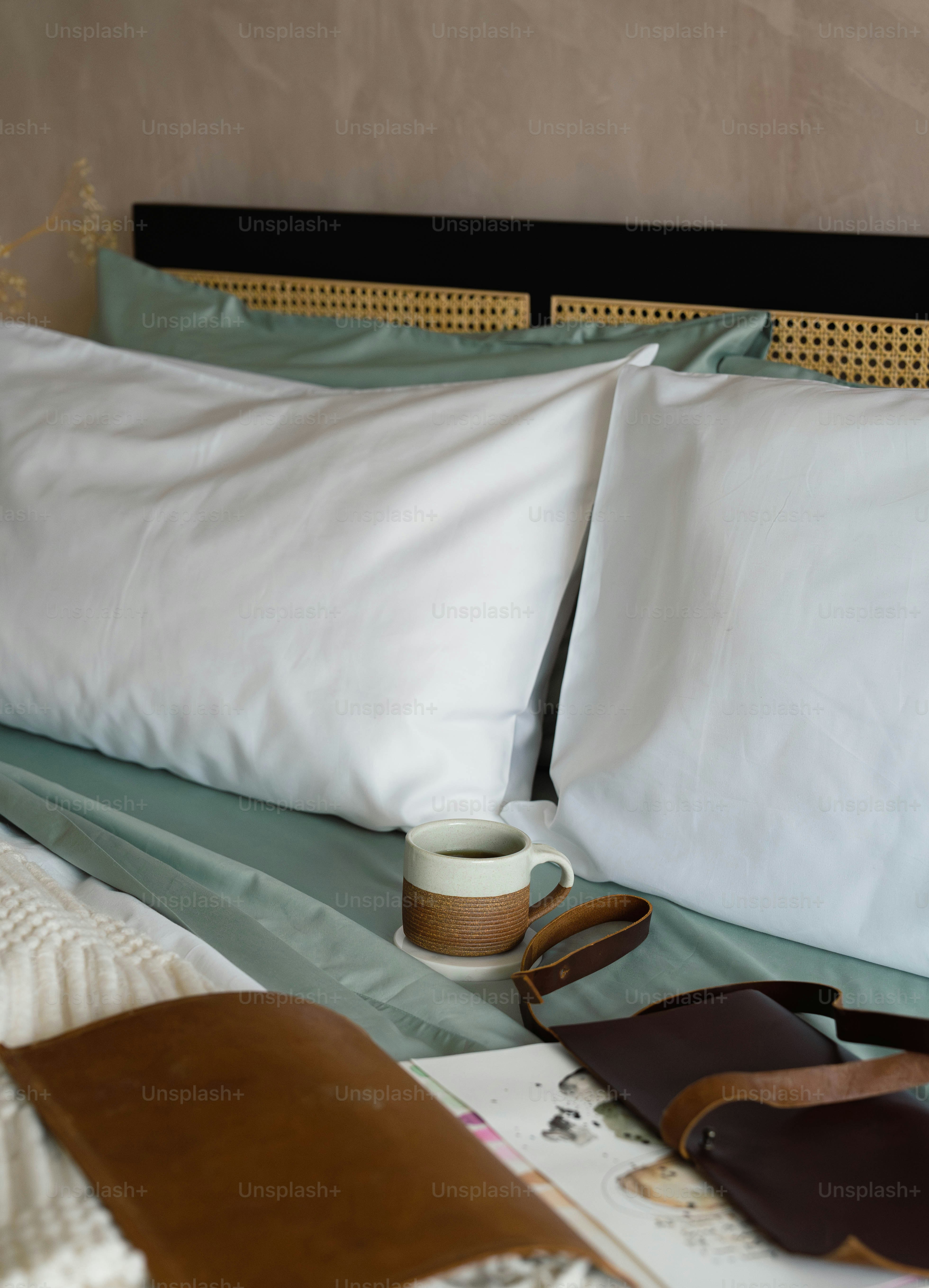 A bed with two pillows and a cup of coffee