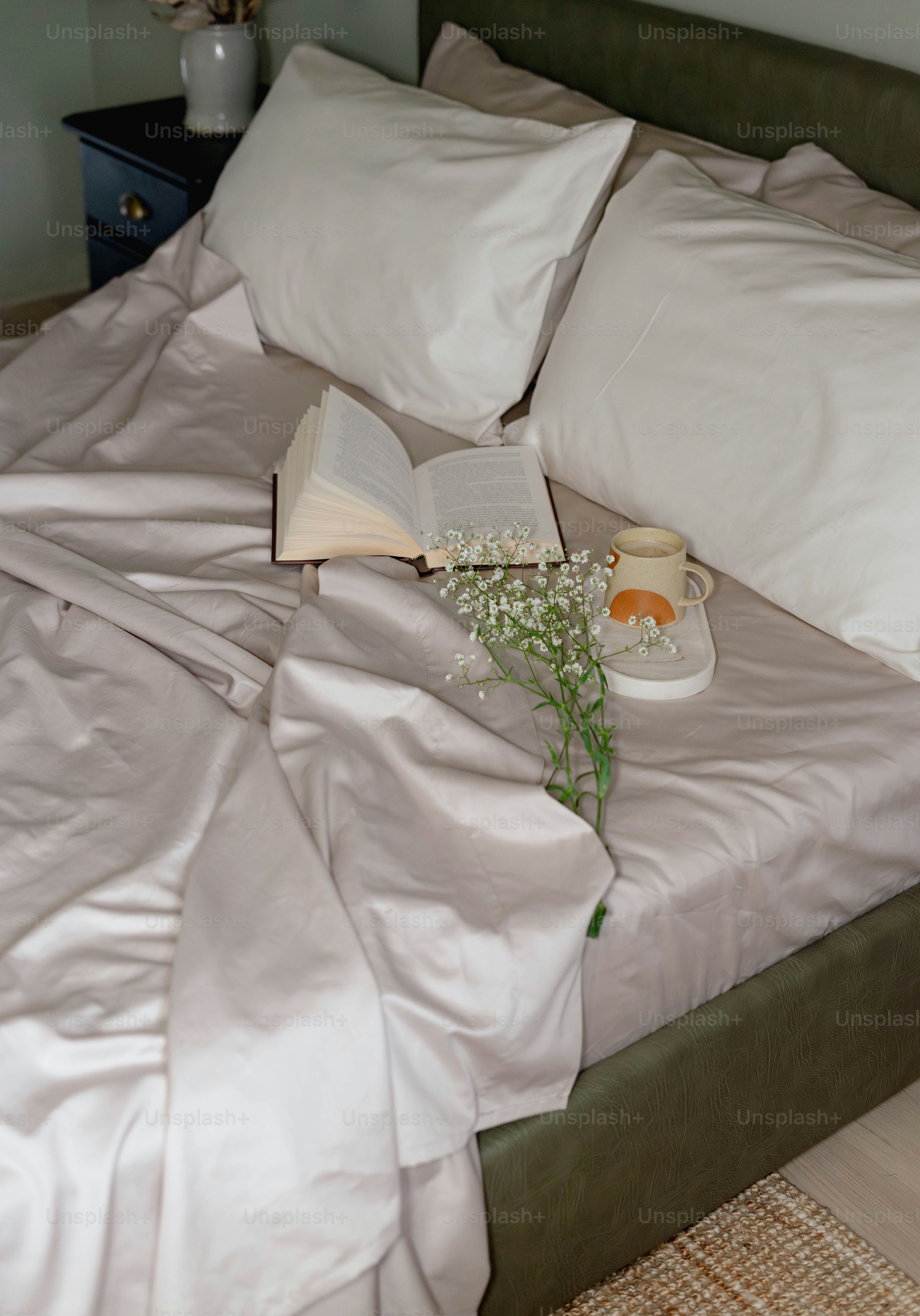 A bed with white sheets and a book on it