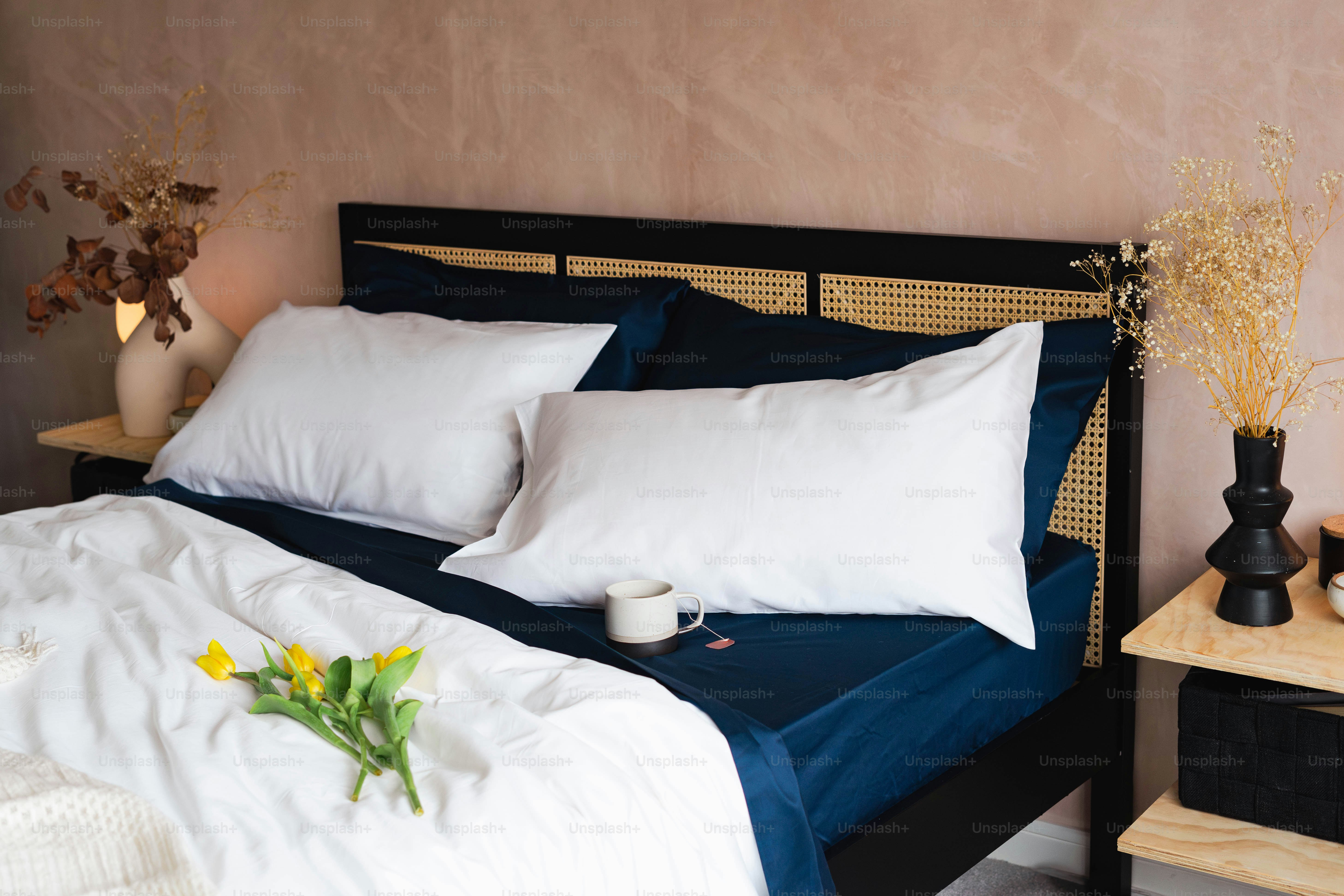 Una cama con almohadas blancas y una manta azul