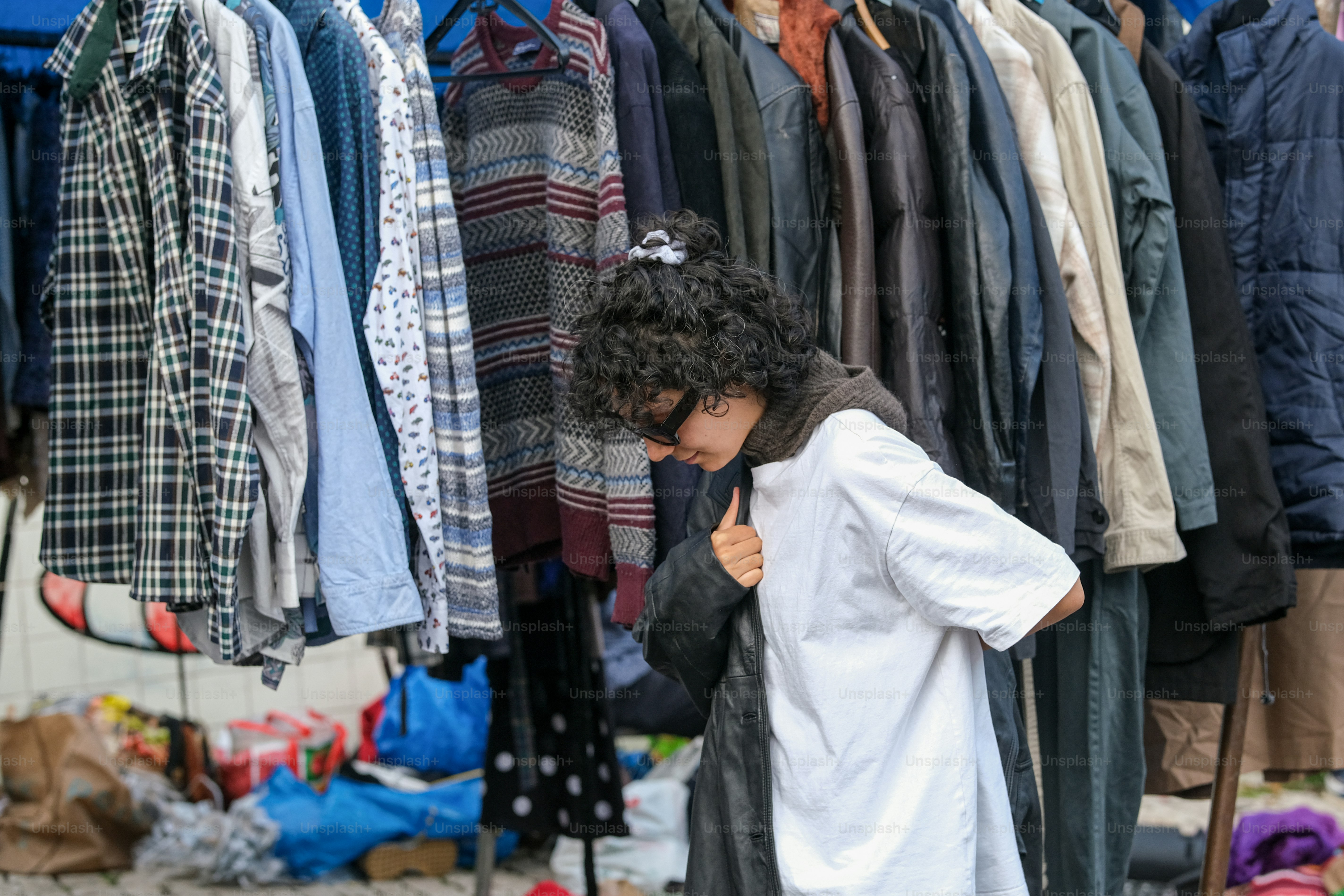 Una persona in piedi davanti a uno scaffale di vestiti
